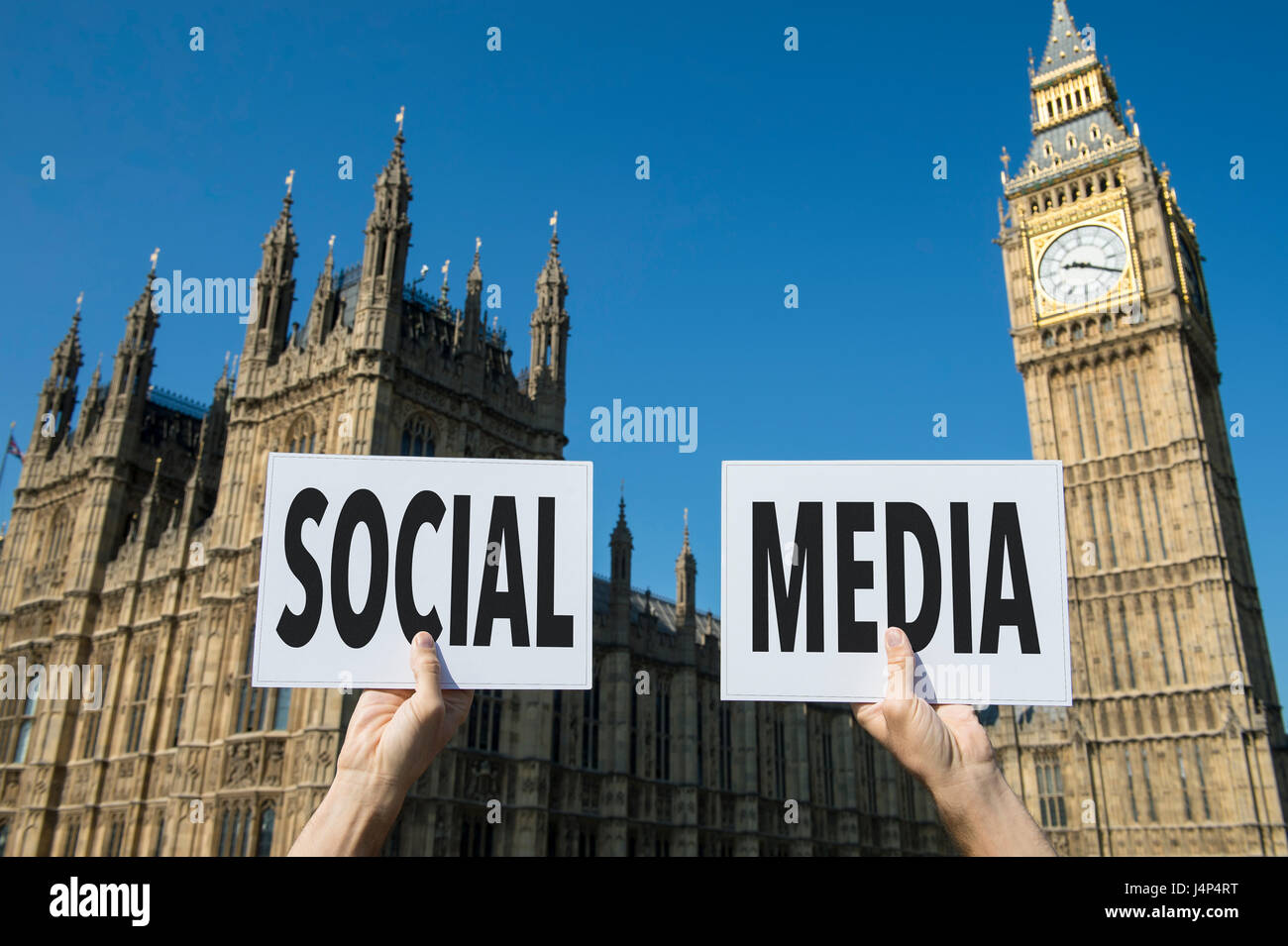 Hands holding up political signboards with the message Social Media in front of Houses of Parliament at Westminster Palace in London, UK Stock Photo