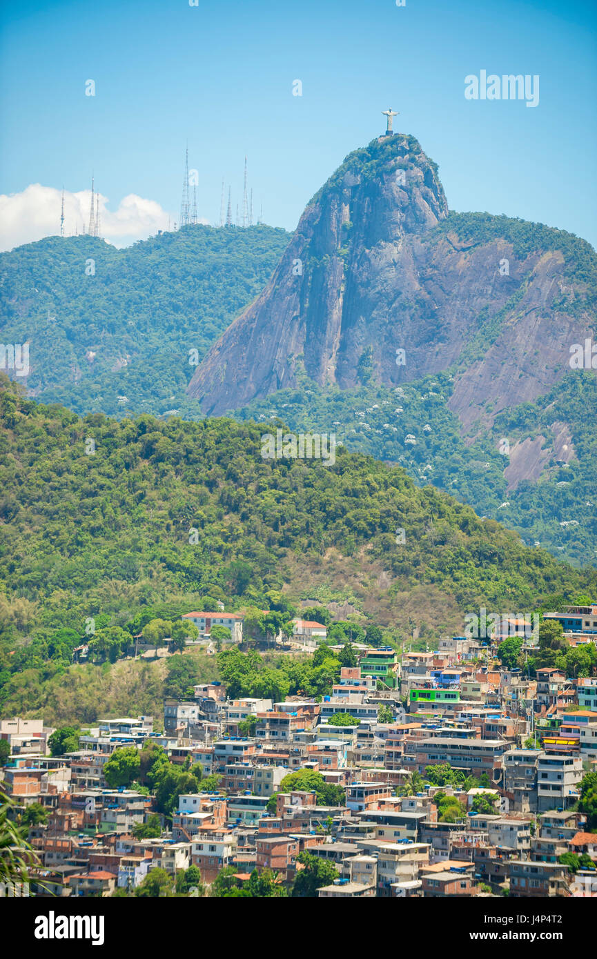Hillside favela community growing up into the jungle in the middle of the city under a dramatic view of Corcovado Mountain in Rio de janeiro, Brazil Stock Photo