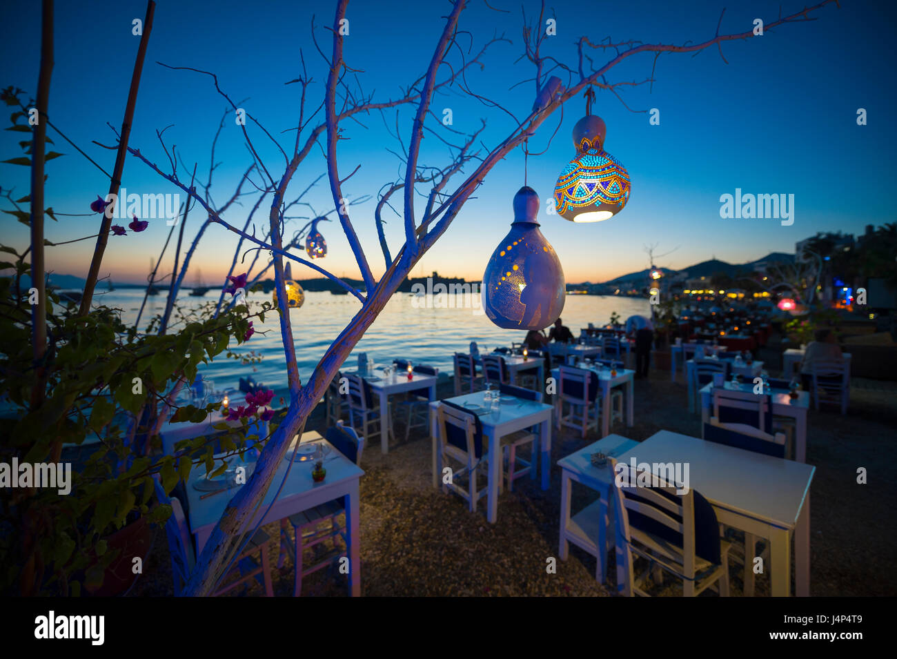 Informal beachside seating with decorative gourd lights hanging from a tree in Bodrum, Turkey Stock Photo