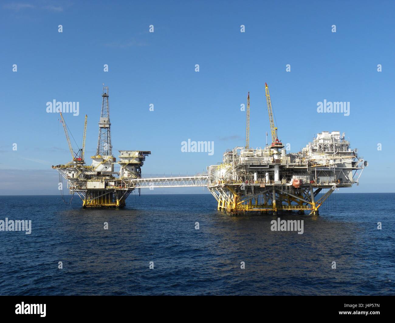 Offshore oil platforms Ellen and Elly off the coast of Long Beach, California. Ellen (right) is a production platform connected by a walkway to Platform Elly (left), a processing platform. Oil production began in 1981 on federal leased land nine miles off the coast of California. Stock Photo