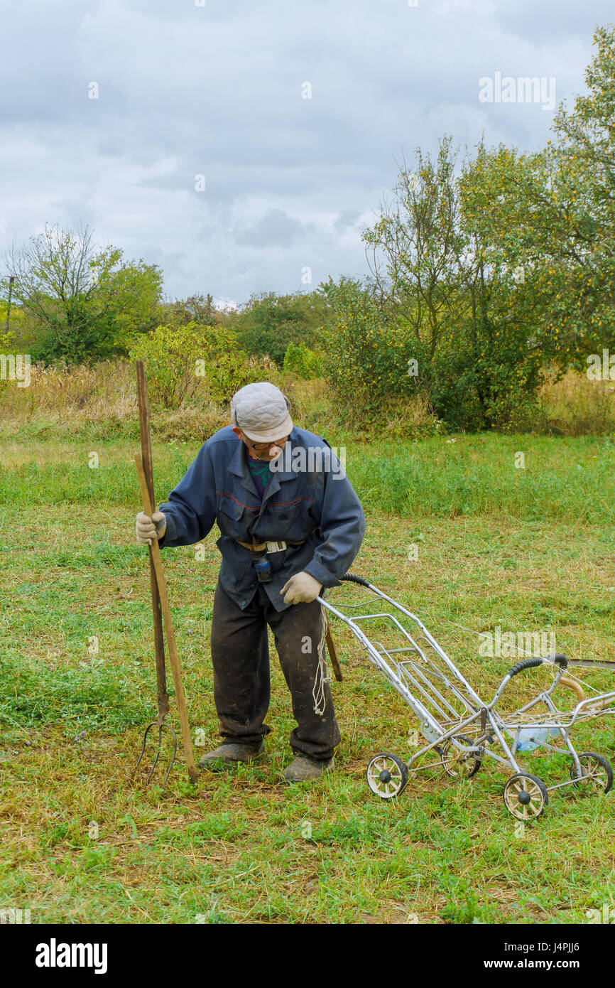 Close up of senior farmer using scythe to mow the lawn traditionally Stock Photo
