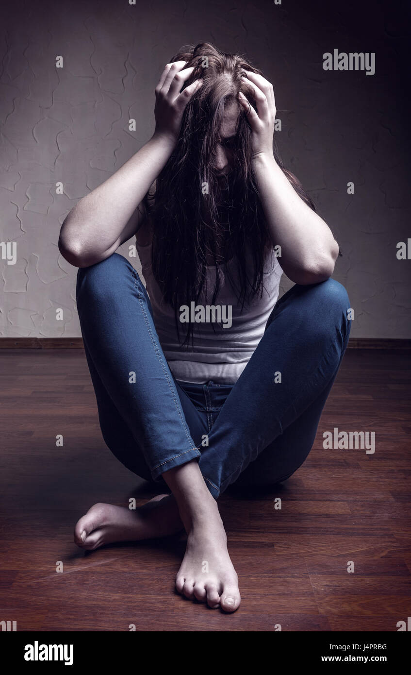 Addict girl sitting on the floor alone Stock Photo