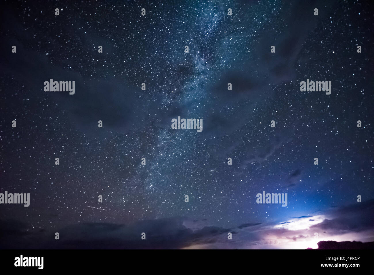 Night sky during thunderstorm in the distance with milky way and stars ...