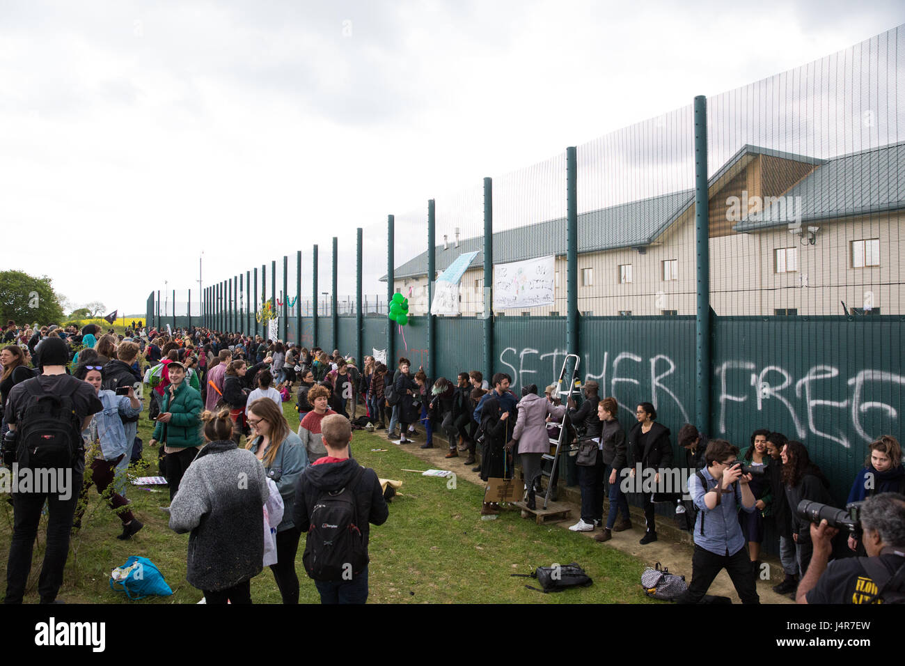 Milton Ernest, UK. 13th May, 2017. Campaigners against immigration detention kick the perimeter fence of Yarl's Wood Immigration Removal Centre during a protest organised by Movement For Justice By Any Means Necessary. Campaigners, including former detainees, called for all immigration detention centres to be closed. Credit: Mark Kerrison/Alamy Live News Stock Photo