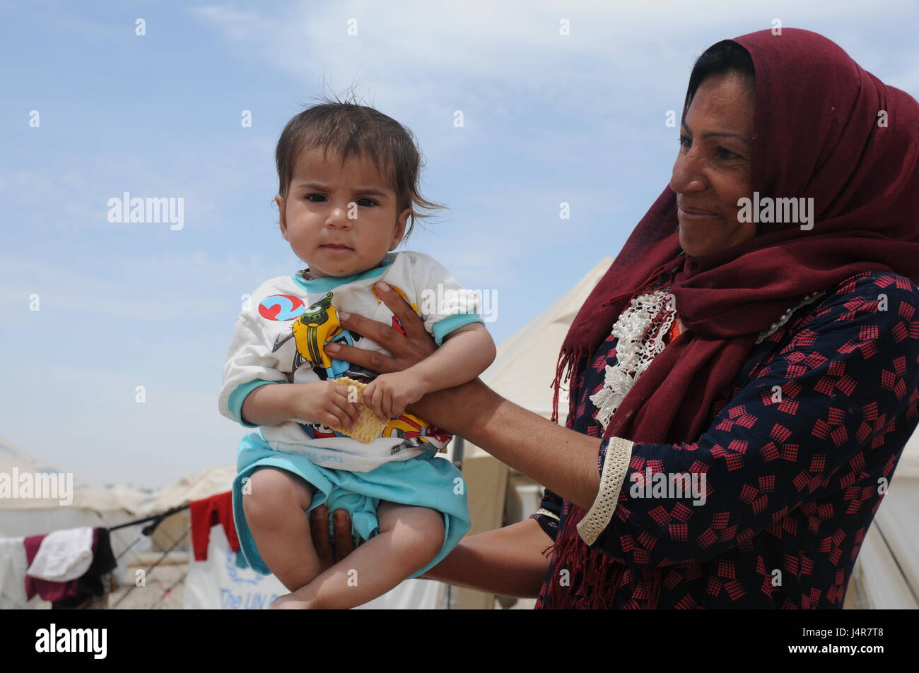 Mosul, Iraq. 13th May, 2017. A woman holds her child in Hassansham U2 Camp, about 30 km east to Mosul, Iraq, on May 13, 2017. The camp has a capacity to accommodate more than 9,000 people when fully occupied. According to Iraqi authorities, more than 630,000 people have been displaced from Mosul and surrounding areas since October 2016, when the military operation began. This includes more than 434,000 displaced from western Mosul since mid-February of this year. Credit: Wei Yudong/Xinhua/Alamy Live News Stock Photo