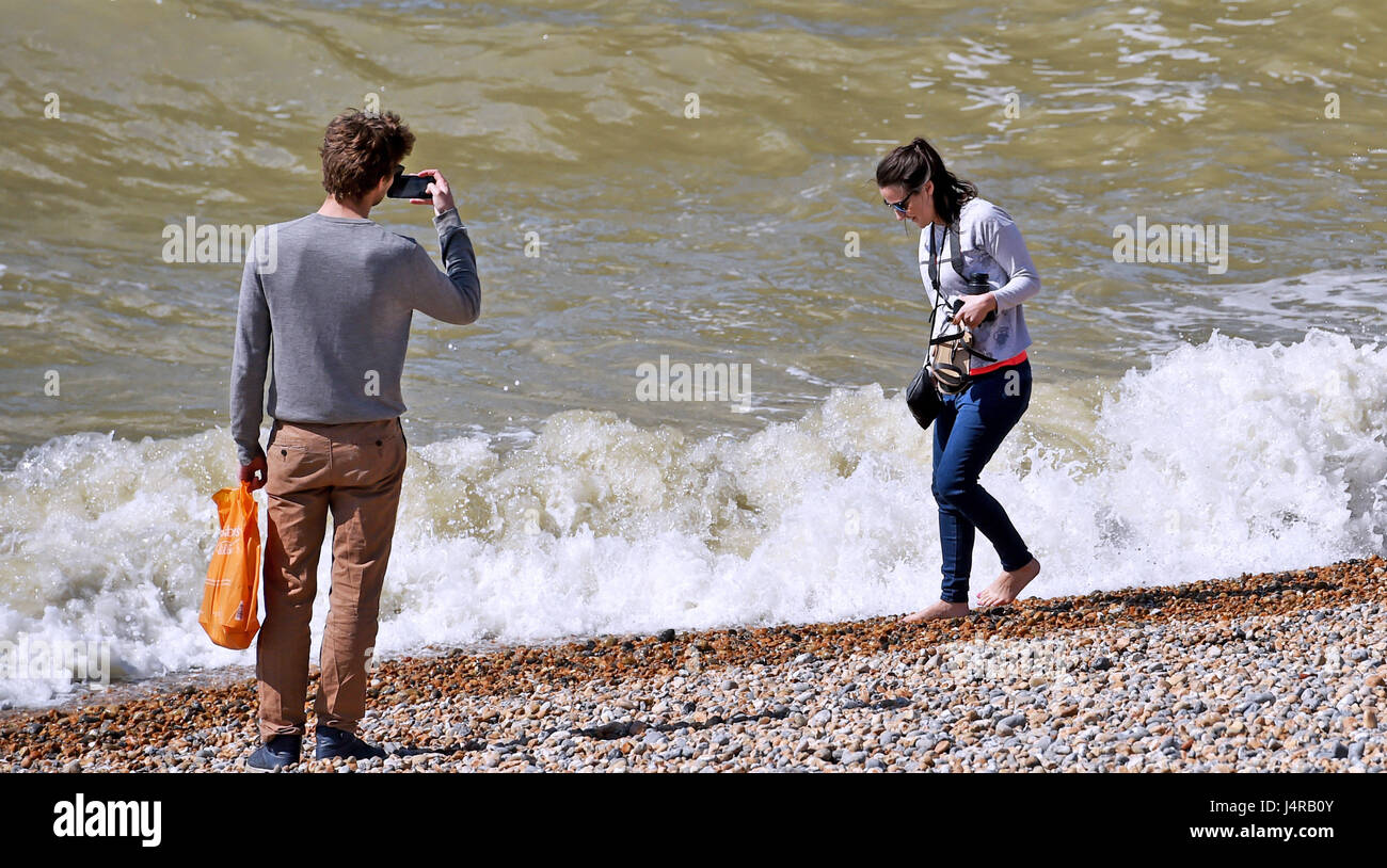 Brighton, UK. 14th May, 2017. A young lady laughs as she gets caught out by a wave while paddling on Brighton beach in beautiful sunny weather with temperatures expected to reach over 20 degrees celsius later in the day . Credit: Simon Dack/Alamy Live News Stock Photo