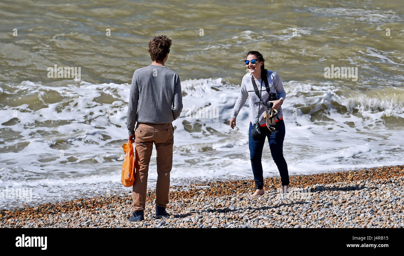 Brighton, UK. 14th May, 2017. A young lady laughs as she gets caught out by a wave while paddling on Brighton beach in beautiful sunny weather with temperatures expected to reach over 20 degrees celsius later in the day . Credit: Simon Dack/Alamy Live News Stock Photo