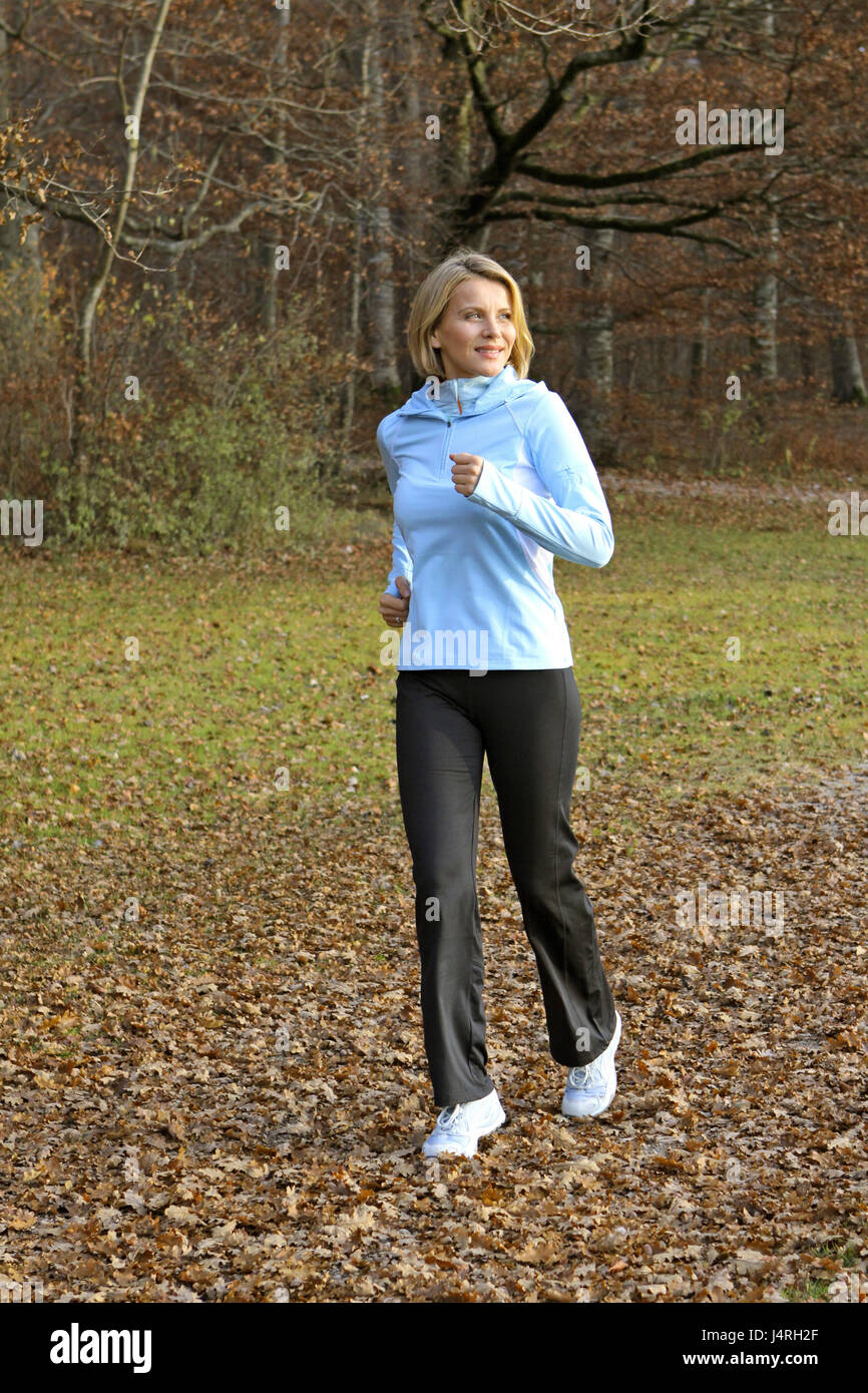 Blond woman, with the jogging in an autumn wood, model released, Stock Photo
