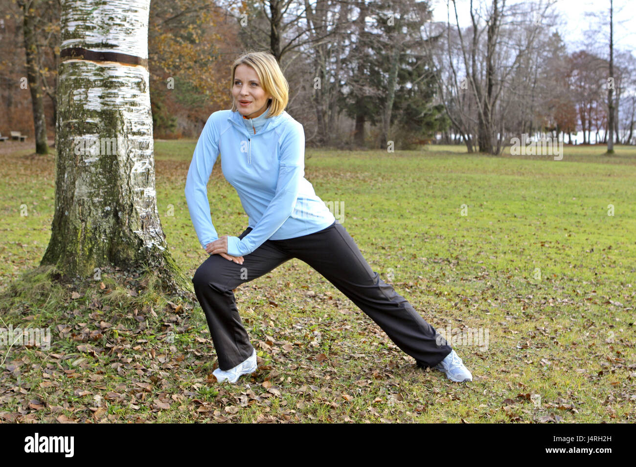Blond woman, with the jogging in an autumn wood, Stretching, model released, Stock Photo