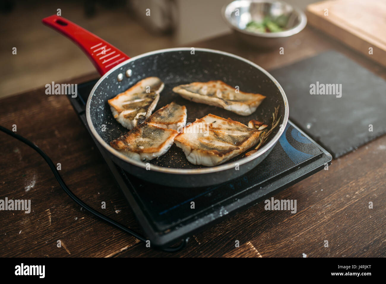Frying pan with fried fish fillet, seafood cooking. Sea bass slices