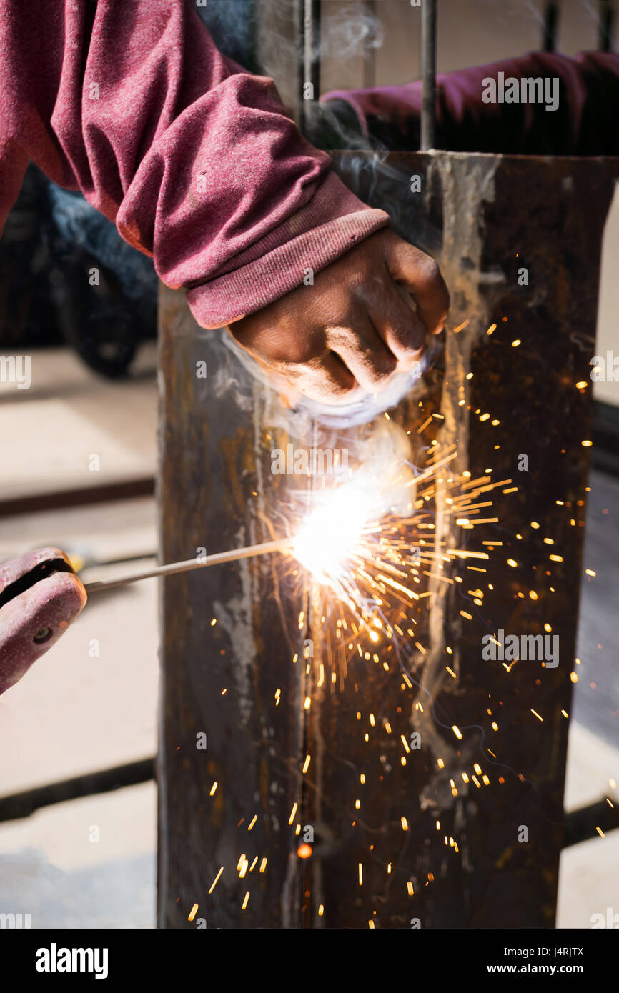 Worker welding steel with spark lighting and smoke at construction site Stock Photo