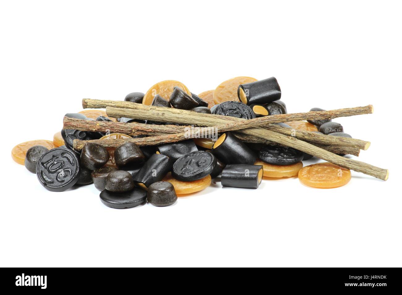 licorice candies with dried sticks of licorice root isolated on white