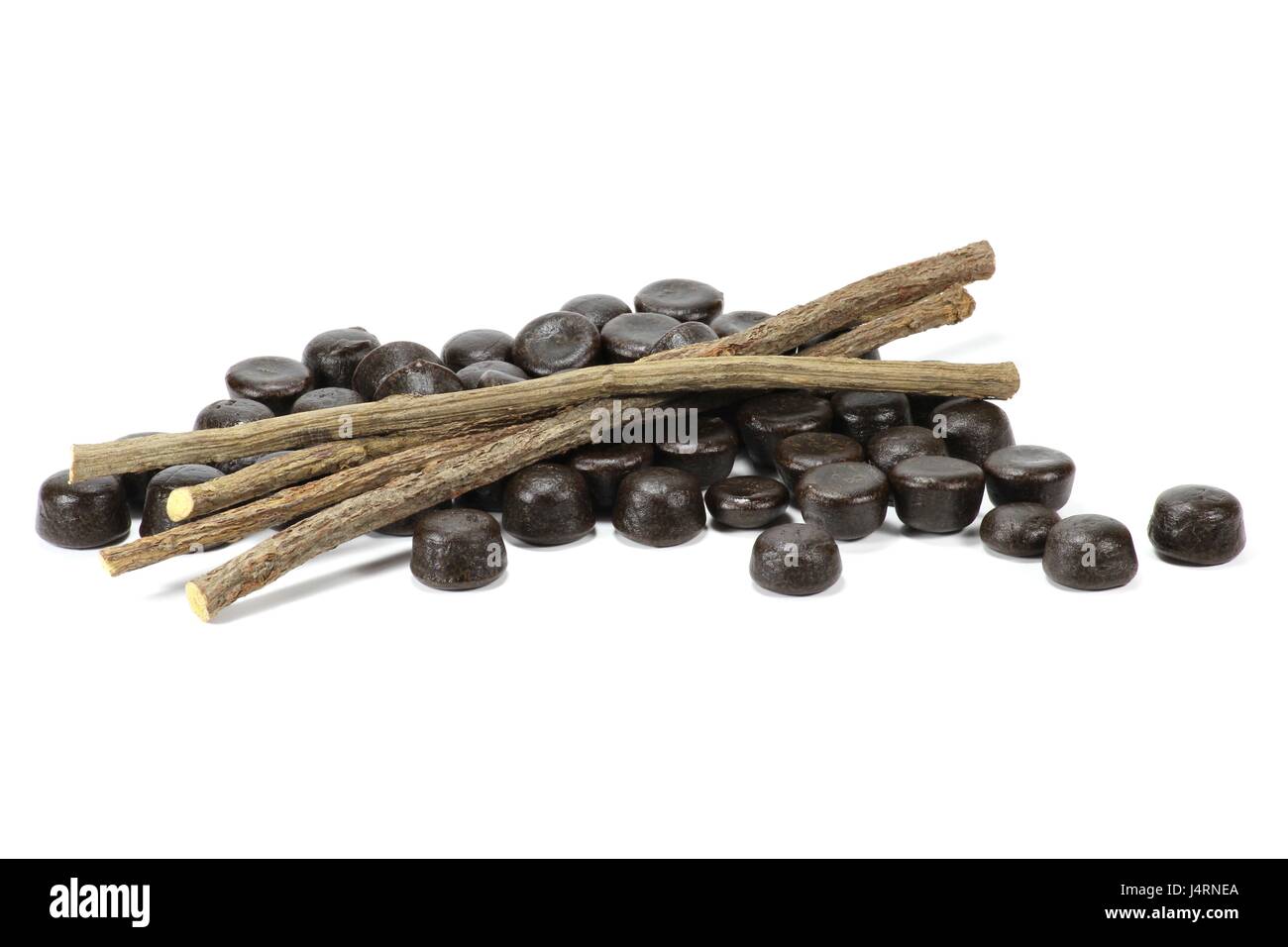 licorice candies with dried sticks of licorice root isolated on white