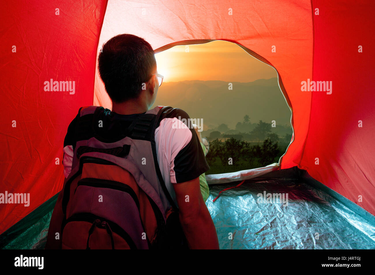 camping man in tent and sun rising sky Stock Photo