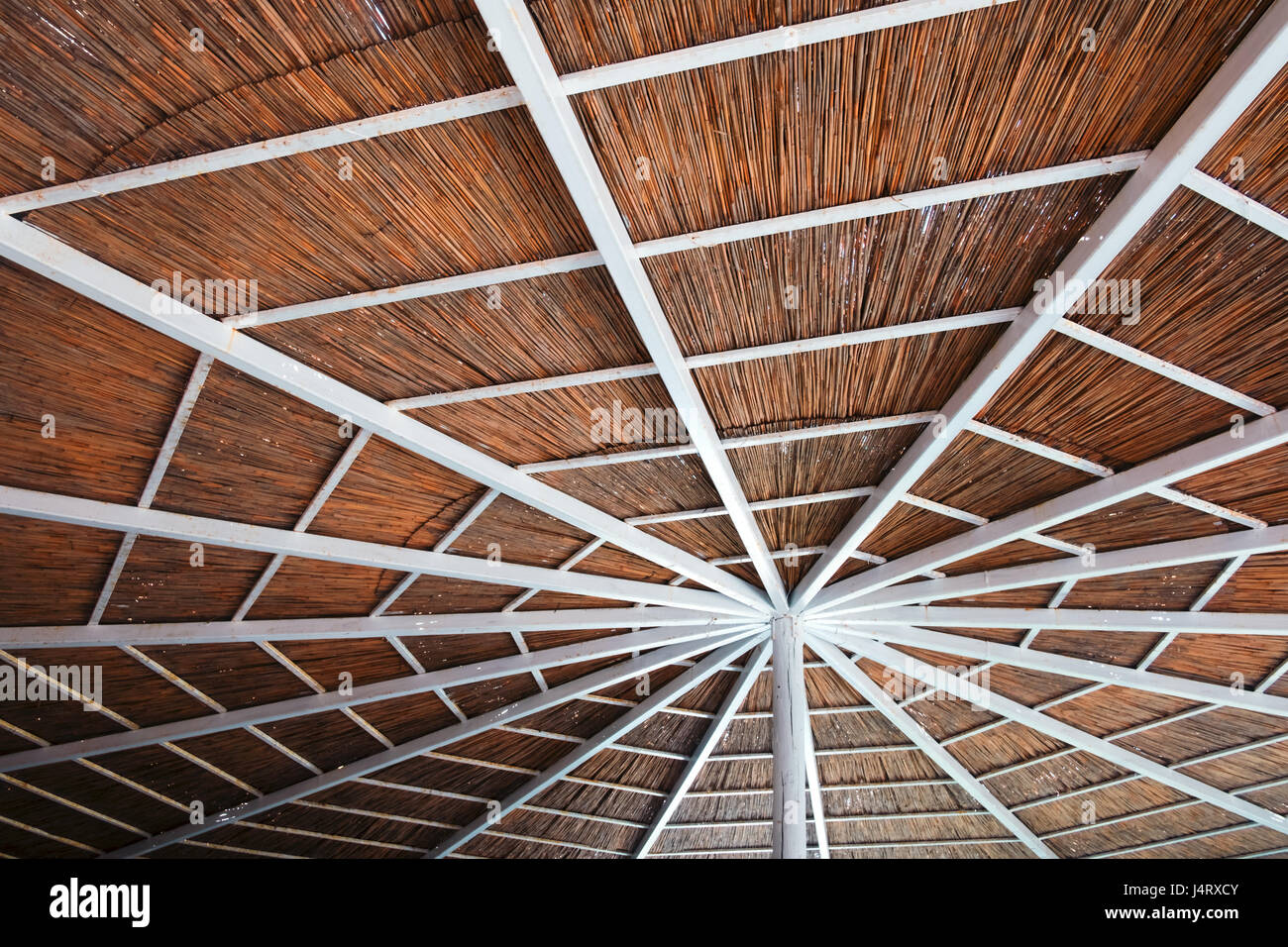 Summer sunshade on beach, near mediterranean sea. White wooden construction with cane roof Stock Photo