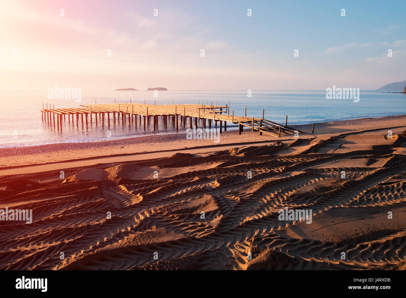 Installation of summer terrace on beach. Breathtaking view on mediterranean sea. Imported sand on a stony beach. Track of wheels Stock Photo