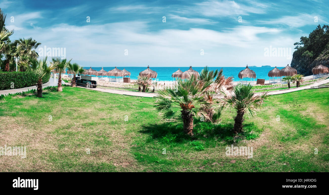 Summer arbors on beach. Breathtaking view on mediterranean sea. White wooden summerhouses on sunny day. Blue sky and fluffy clouds Stock Photo