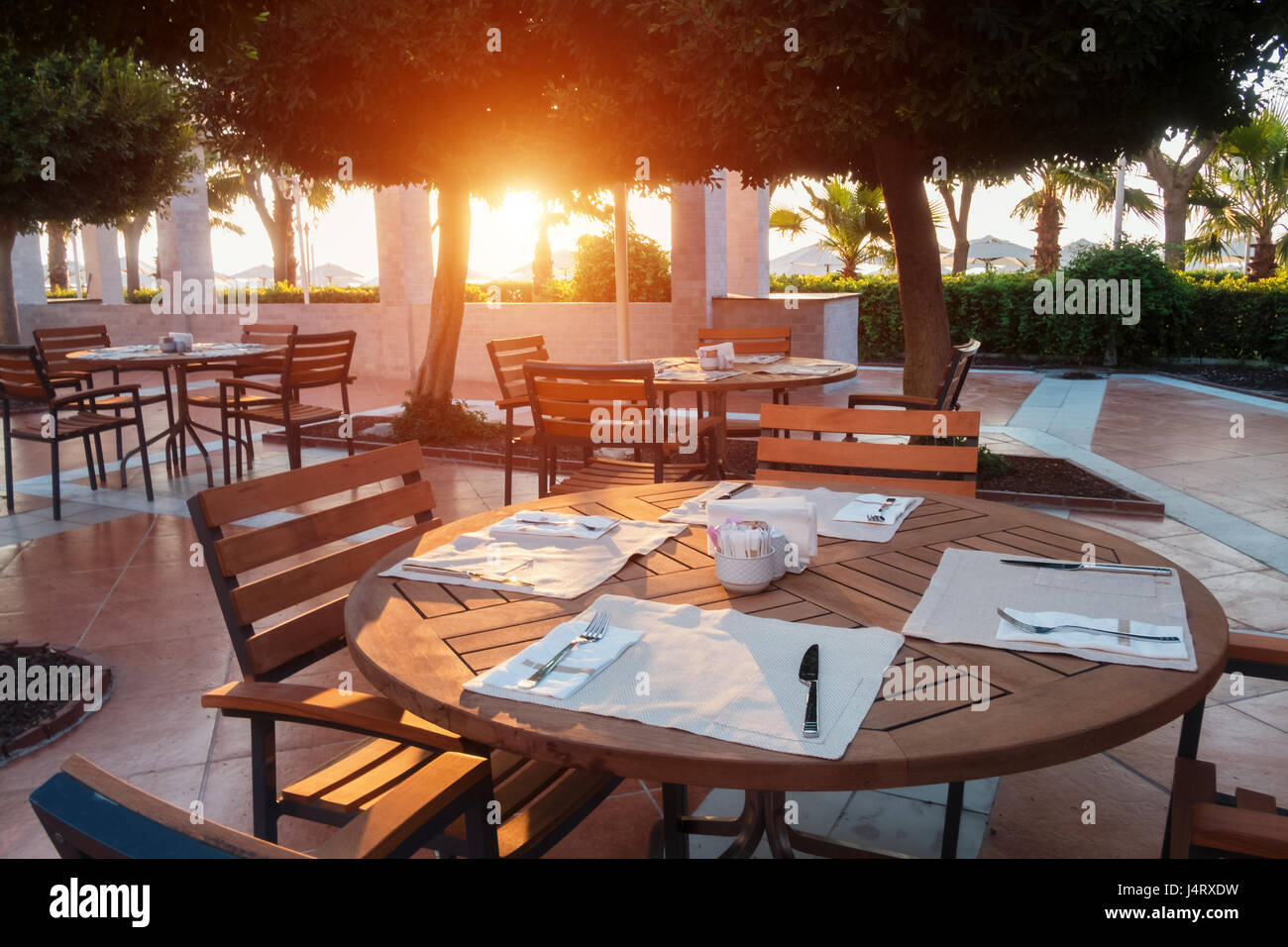Summer restaurant on beach, near mediterranean sea. Wooden furniture and white napkin Stock Photo