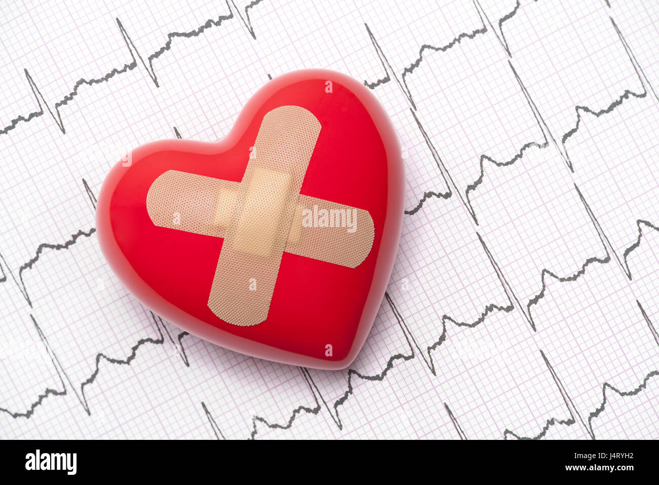 Red heart with adhesive plaster on electrocardiogram (ECG, EKG) Stock Photo