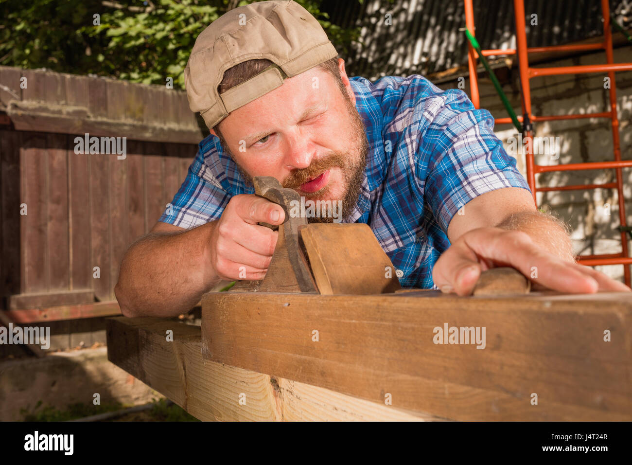 Carpenter chipping the wooden plank by the plane Stock Photo Alamy