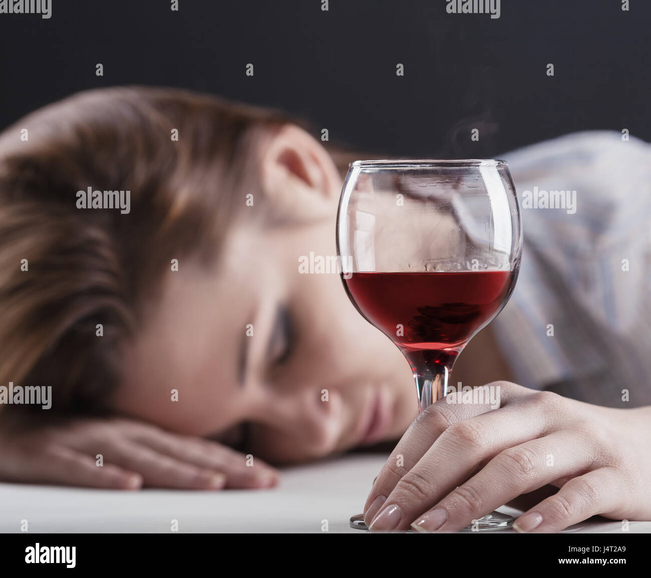 Young beautiful woman in depression, drinking alcohol on dark background Stock Photo