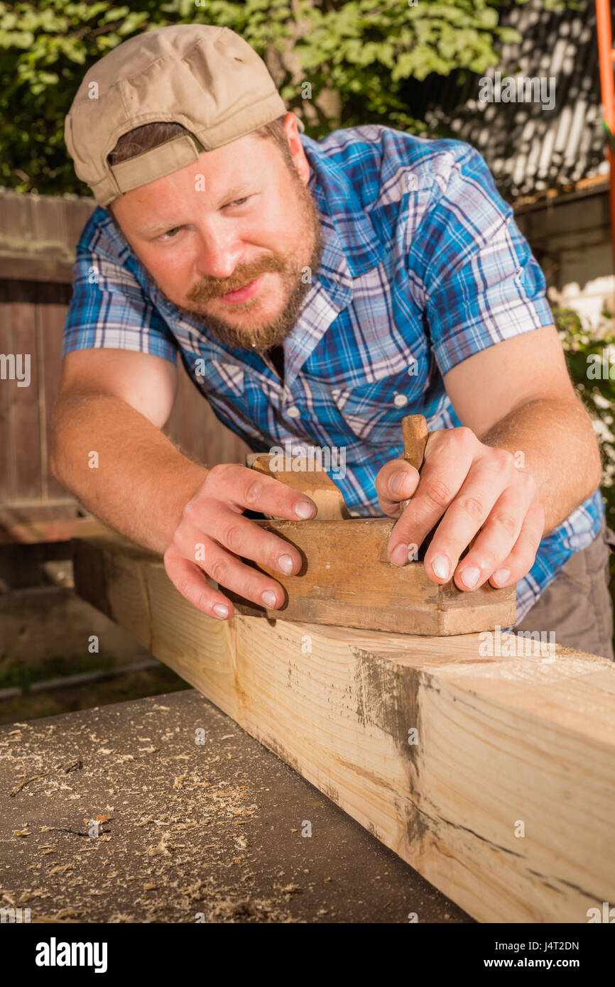 Carpenter chipping the wooden plank by the plane Stock Photo Alamy