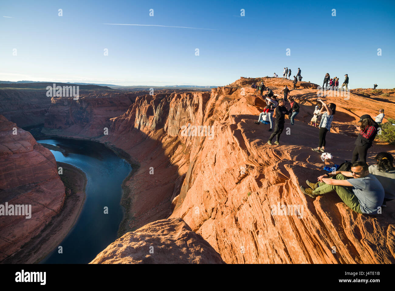 Tourists Admiring The View At Horseshoe Bend at sunset with the Colorado river in shadow, Arizona Stock Photo