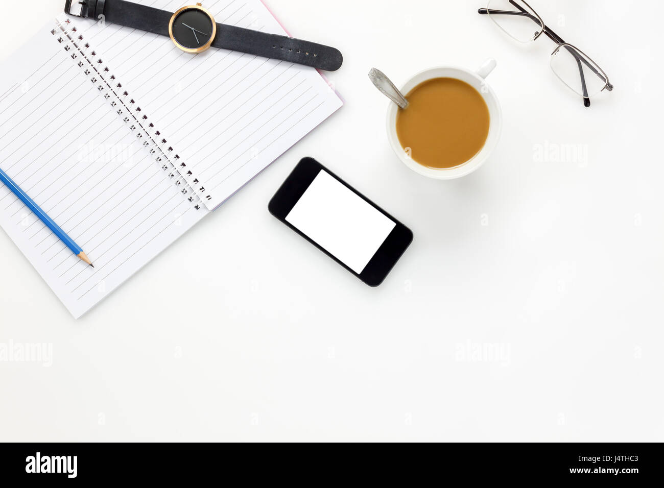 Top view business office desk.mobile phone,eyeglasses,watch,coffee,notebook,pencil on white office desk with copy space. Stock Photo