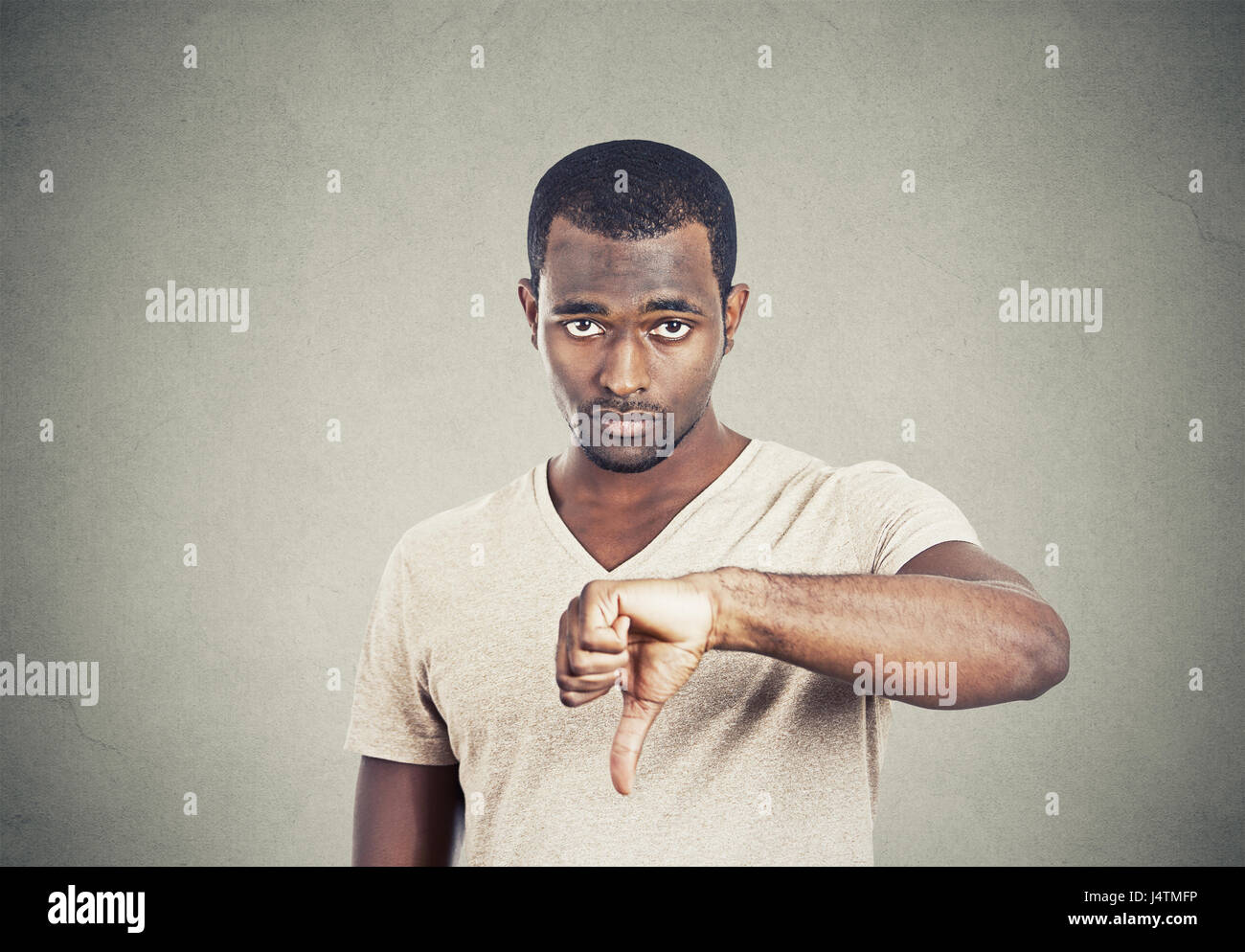 Closeup portrait unhappy, angry annoyed, grumpy man giving thumbs down gesture, looking with negative facial expression disapproval isolated on grey w Stock Photo