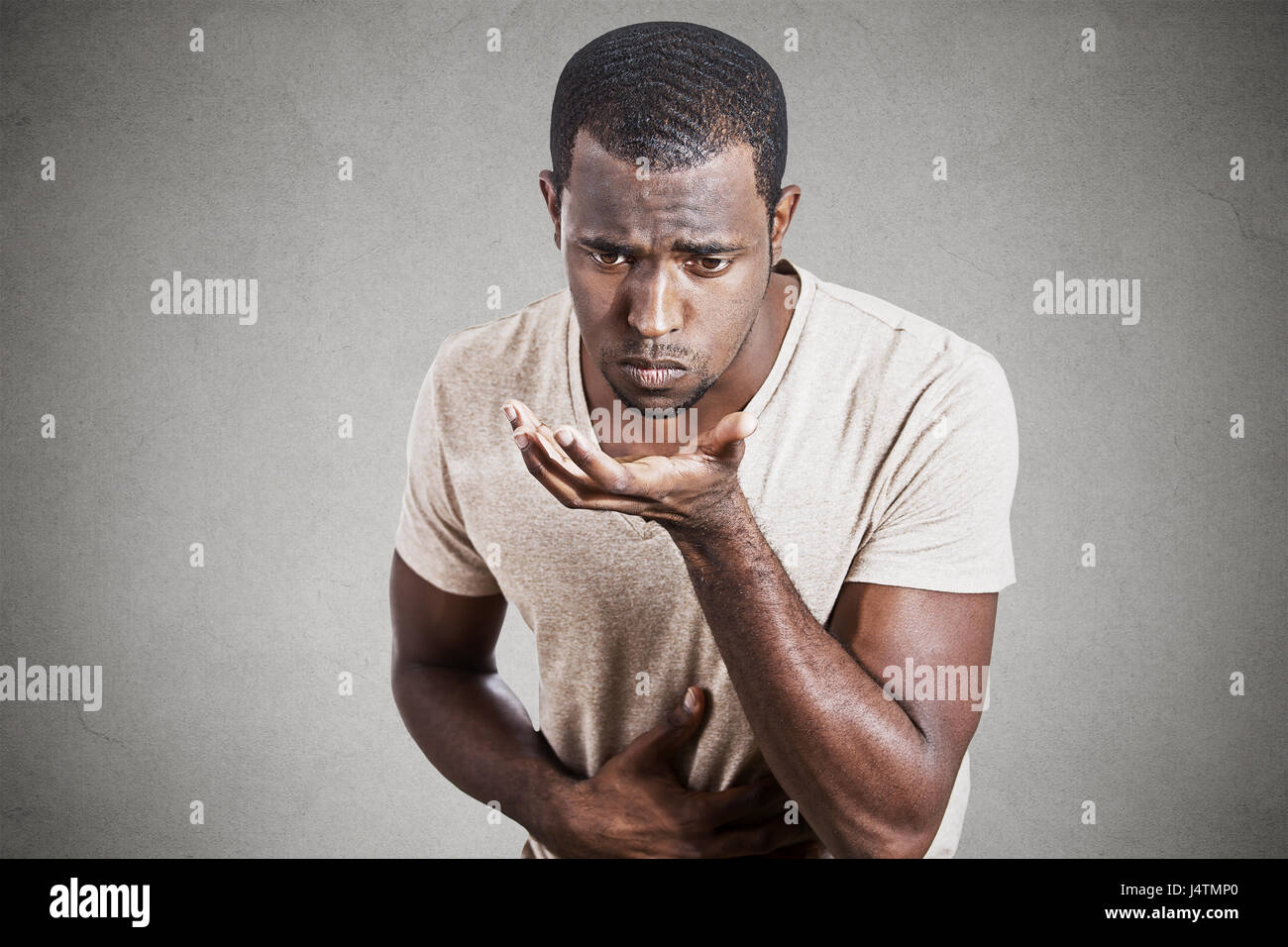 Closeup portrait young unhappy sick man about to chuck, throw up, retch barf isolated on gray wall background. Negative human emotion feeling facial e Stock Photo