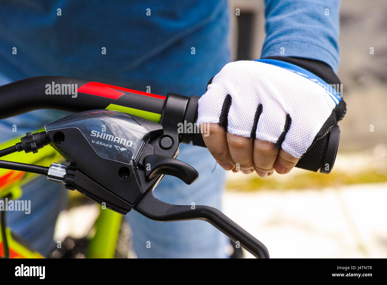 Tambov, Russian Federation - May 07, 2017 Child hand with glove on handlebars with Shimano speed shift and brake lever. Stock Photo