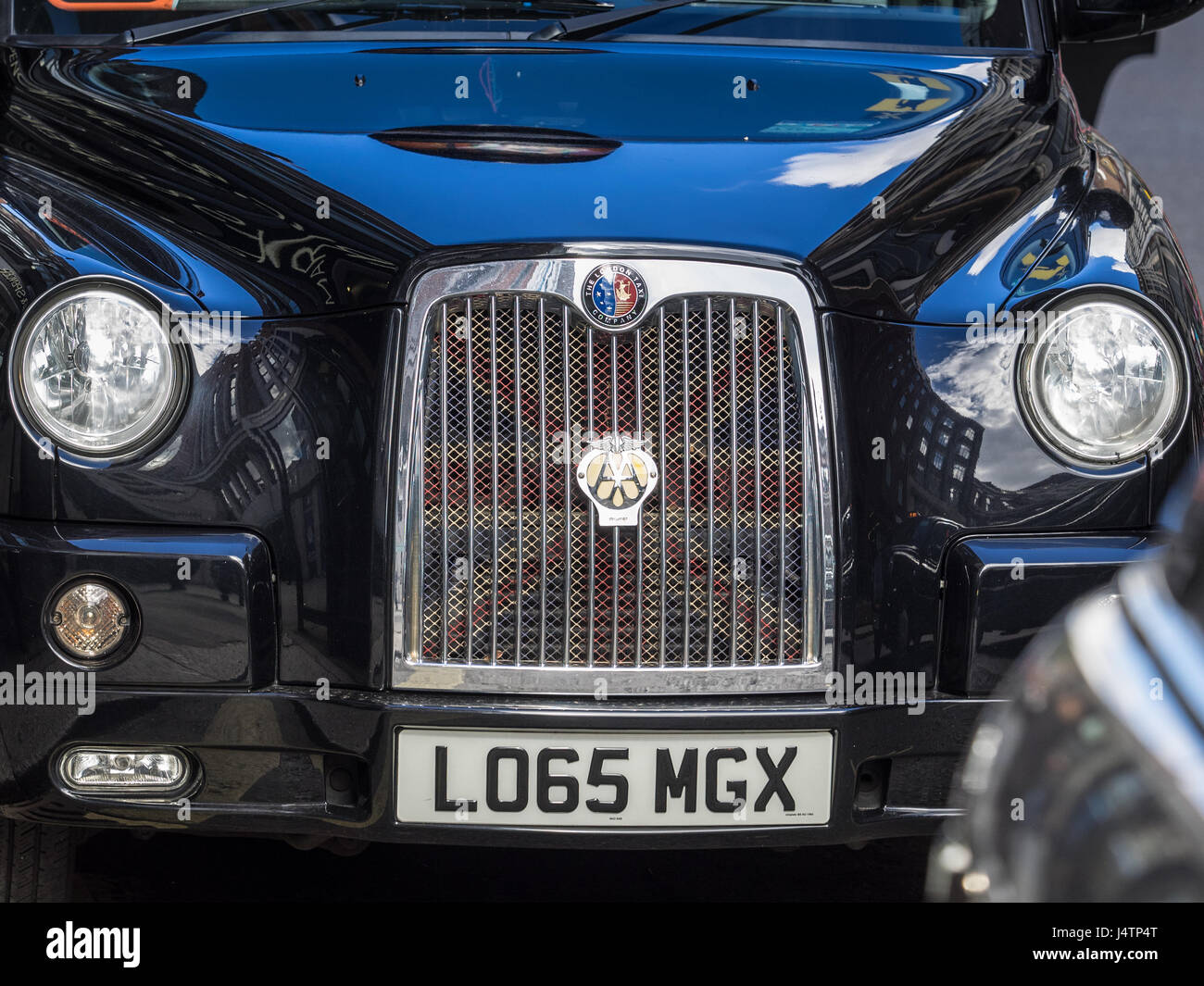 A London Taxi (Black Cab) with a distinctive Union Jack flag design on the radiator grille. Stock Photo