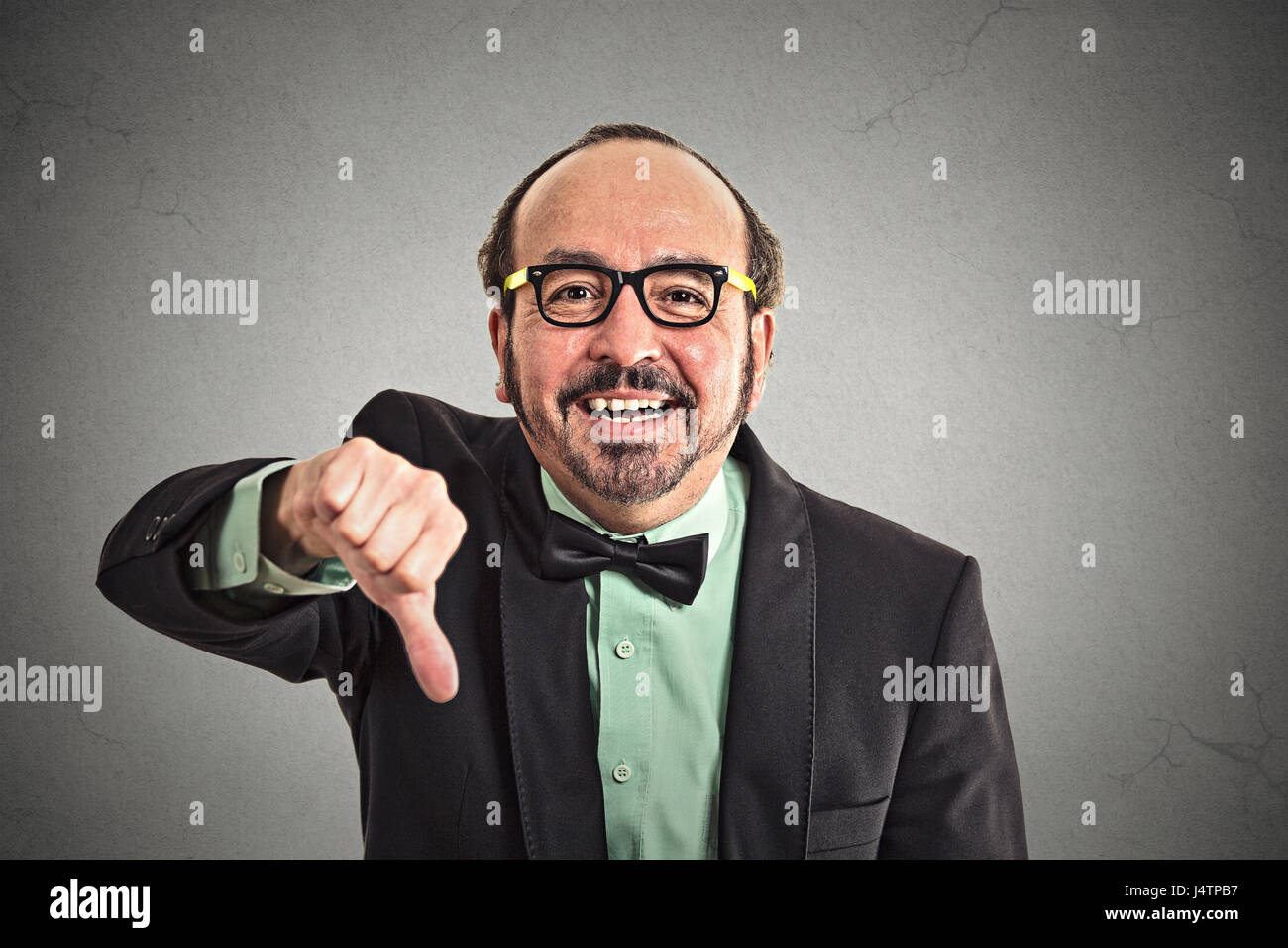 Closeup portrait sarcastic middle aged man showing thumbs down sign hand gesture happy someone made mistake lost failed isolated grey wall background. Stock Photo
