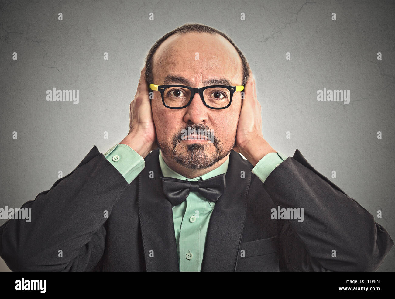 Closeup portrait middle aged business man with glasses covering his ears with hands closed mouth isolated grey wall background. Hear no evil concept.  Stock Photo