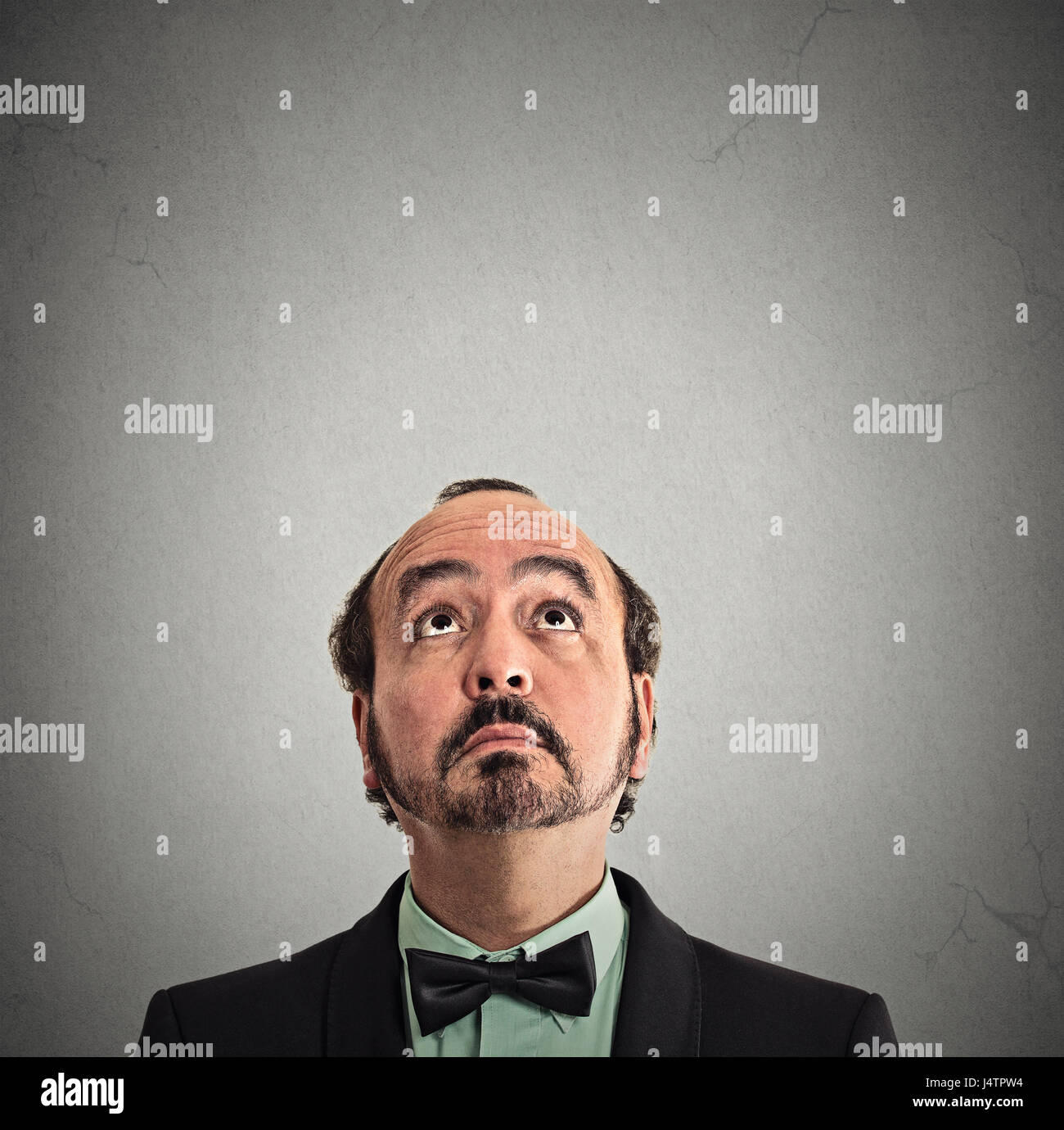 closeup portrait headshot middle aged man looking up isolated on grey wall background with copy space above head. Human face expressions, emotions, fe Stock Photo