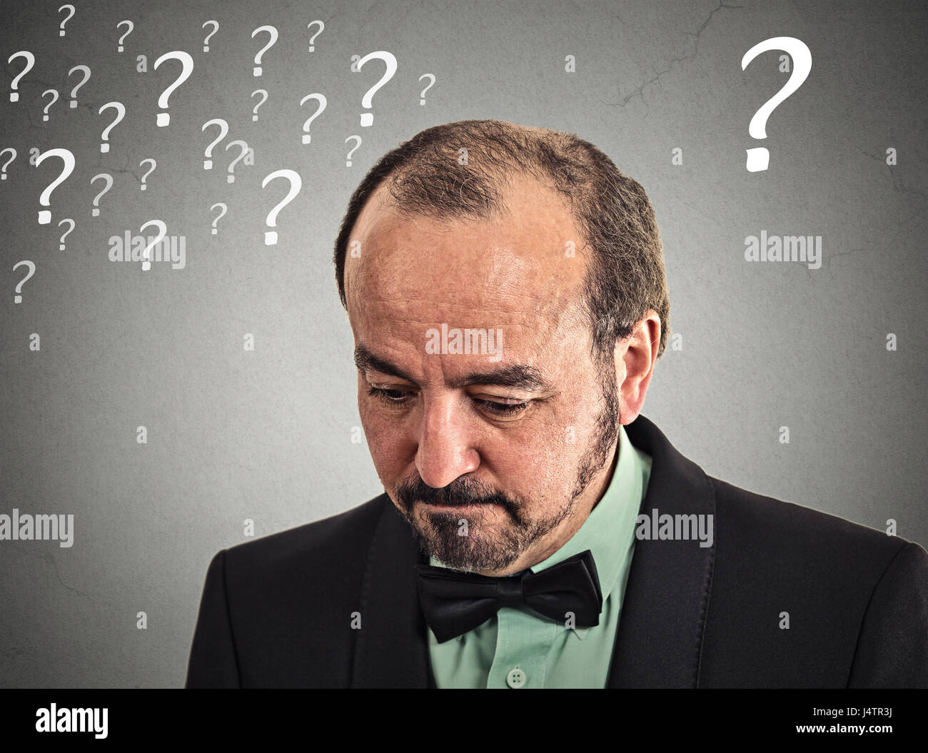 Closeup portrait headshot sad, depressed, desperate, alone, disappointed in life middle aged man looking down isolated grey wall background with quest Stock Photo