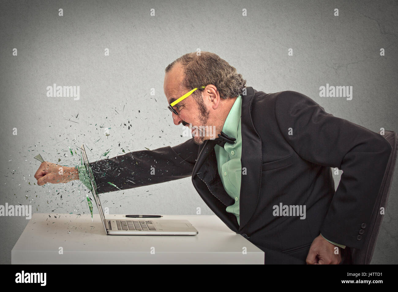 furious businessman throws a punch into computer screaming isolated