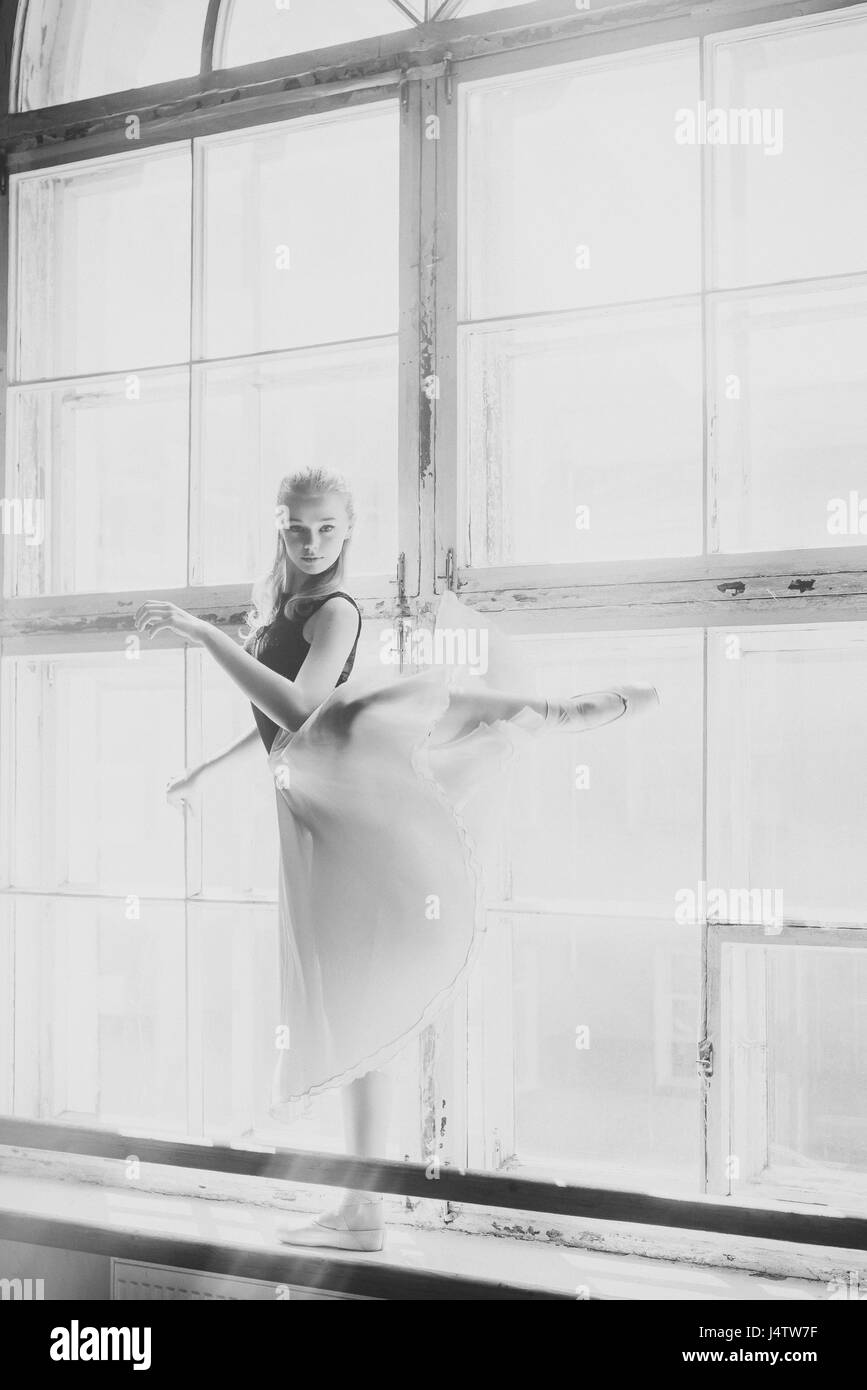 Ballerina dancing at window sill background. Girl in a turquoise ballet skirt. Black and white photo. Stock Photo