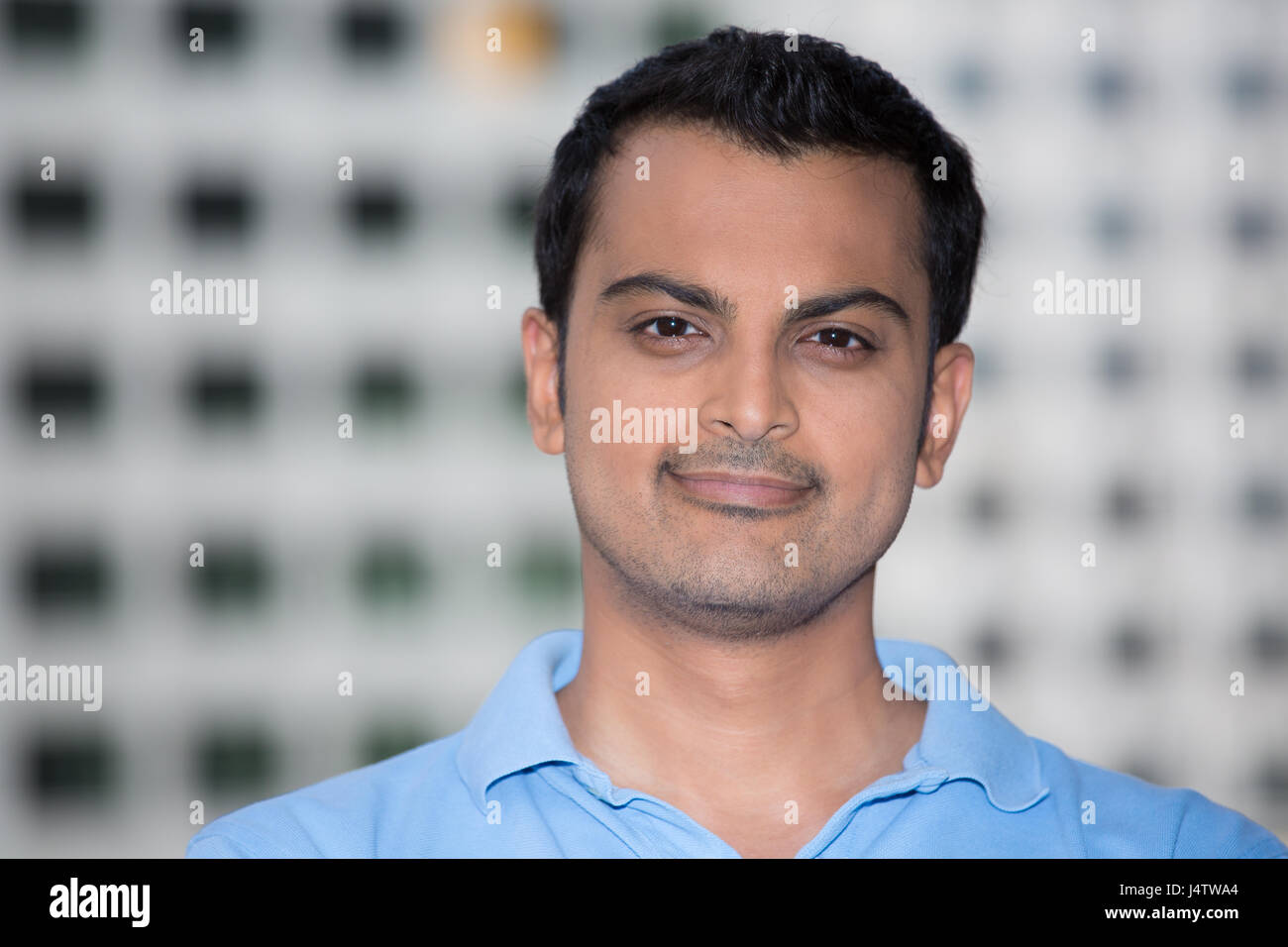 Closeup headshot portrait, happy handsome business man, smiling, in light blue polo shirt, confident and friendly, isolated white building background. Stock Photo