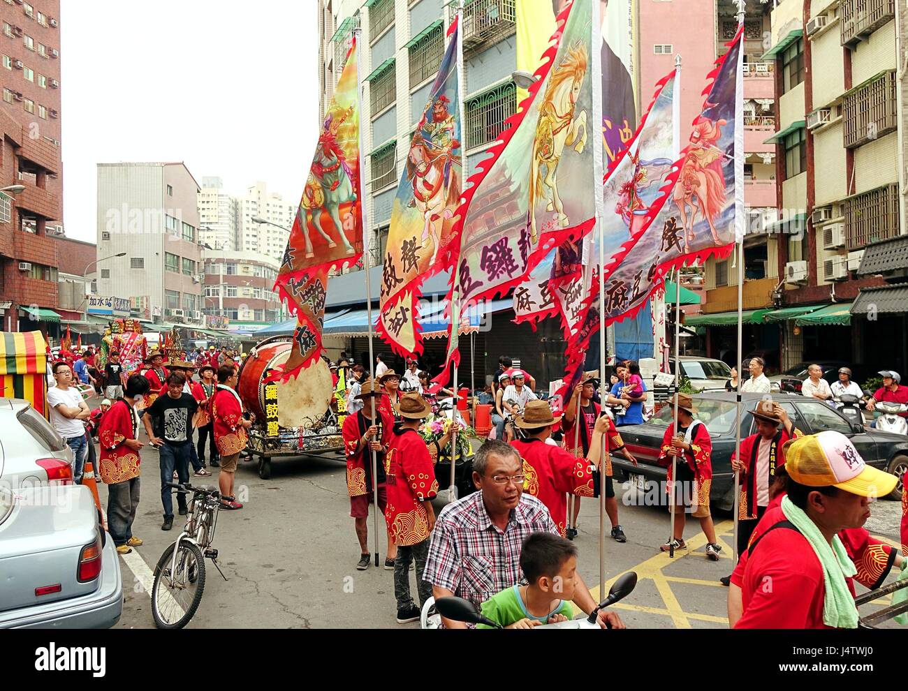 KAOHSIUNG, TAIWAN -- APRIL 20, 2014: A religious procession with flags and drums makes its way through a narrow street. Stock Photo