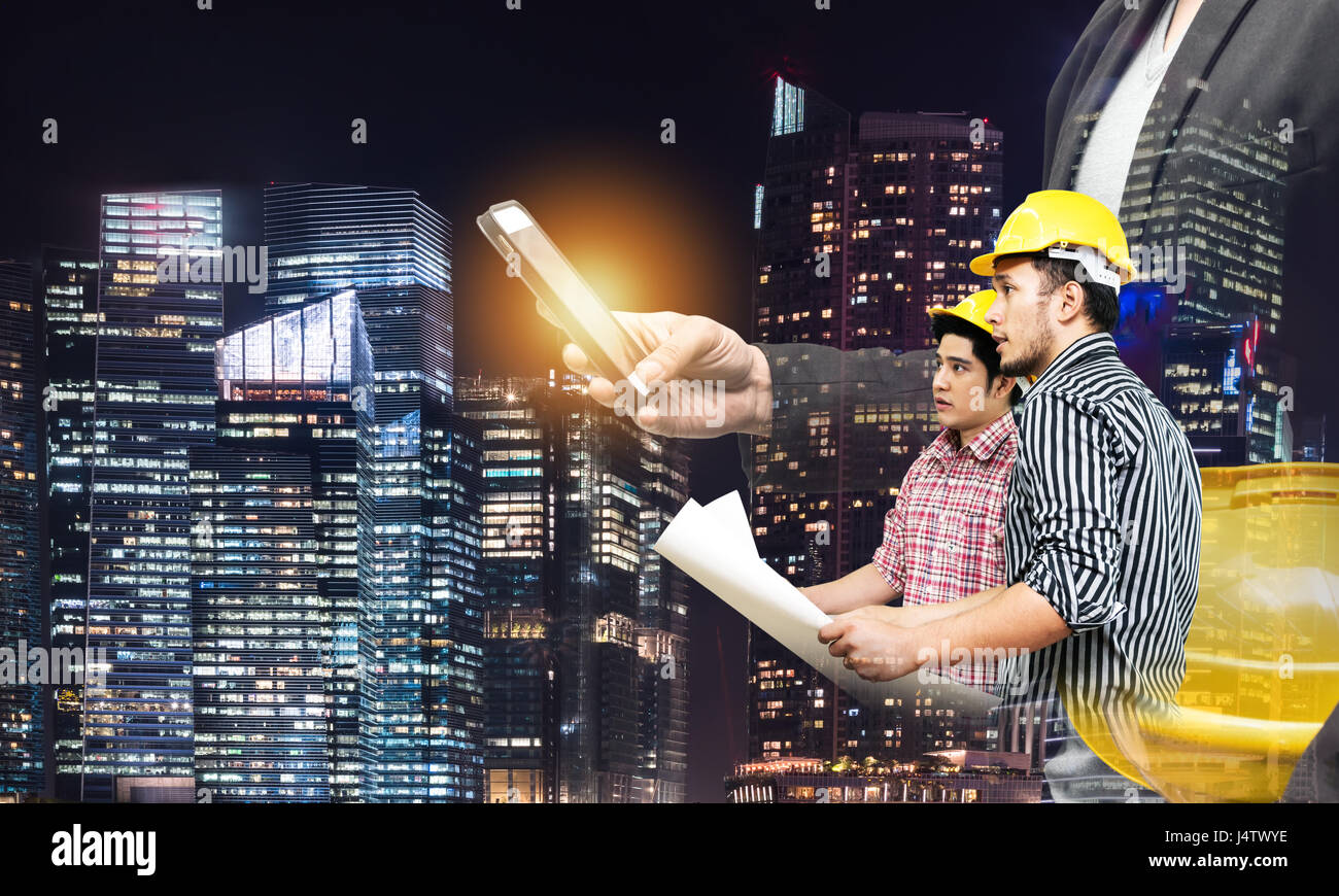 Smart construction in industry 4.0 concept. Double exposure of business man hand using mobile phone and two engineers worker with graphic popup,drone, Stock Photo