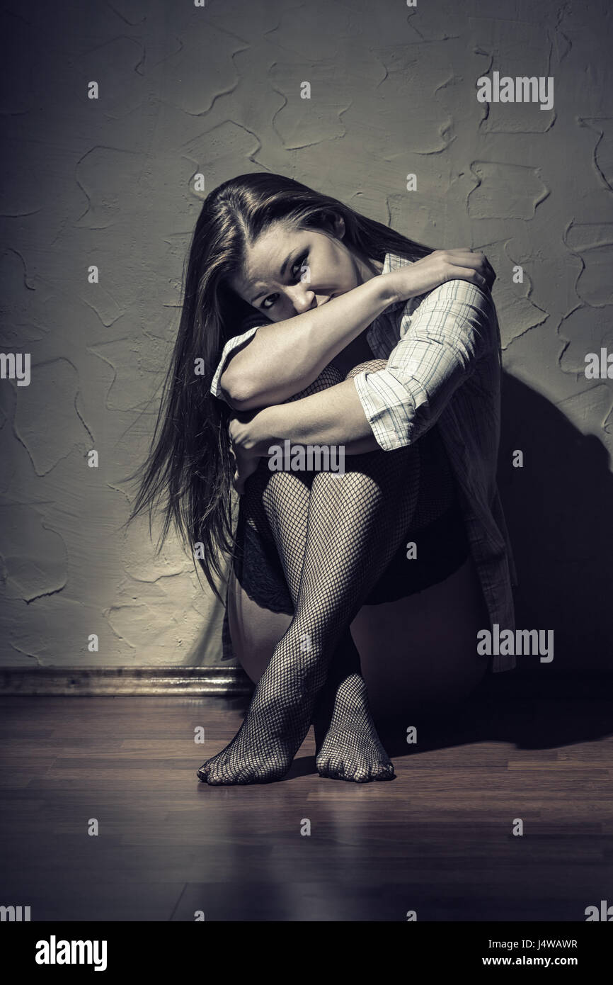 Sad young woman sitting alone in a empty room Stock Photo