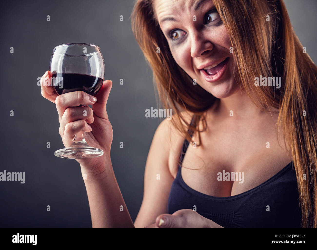 Cheerful drunk young woman. Focus on the glass Stock Photo