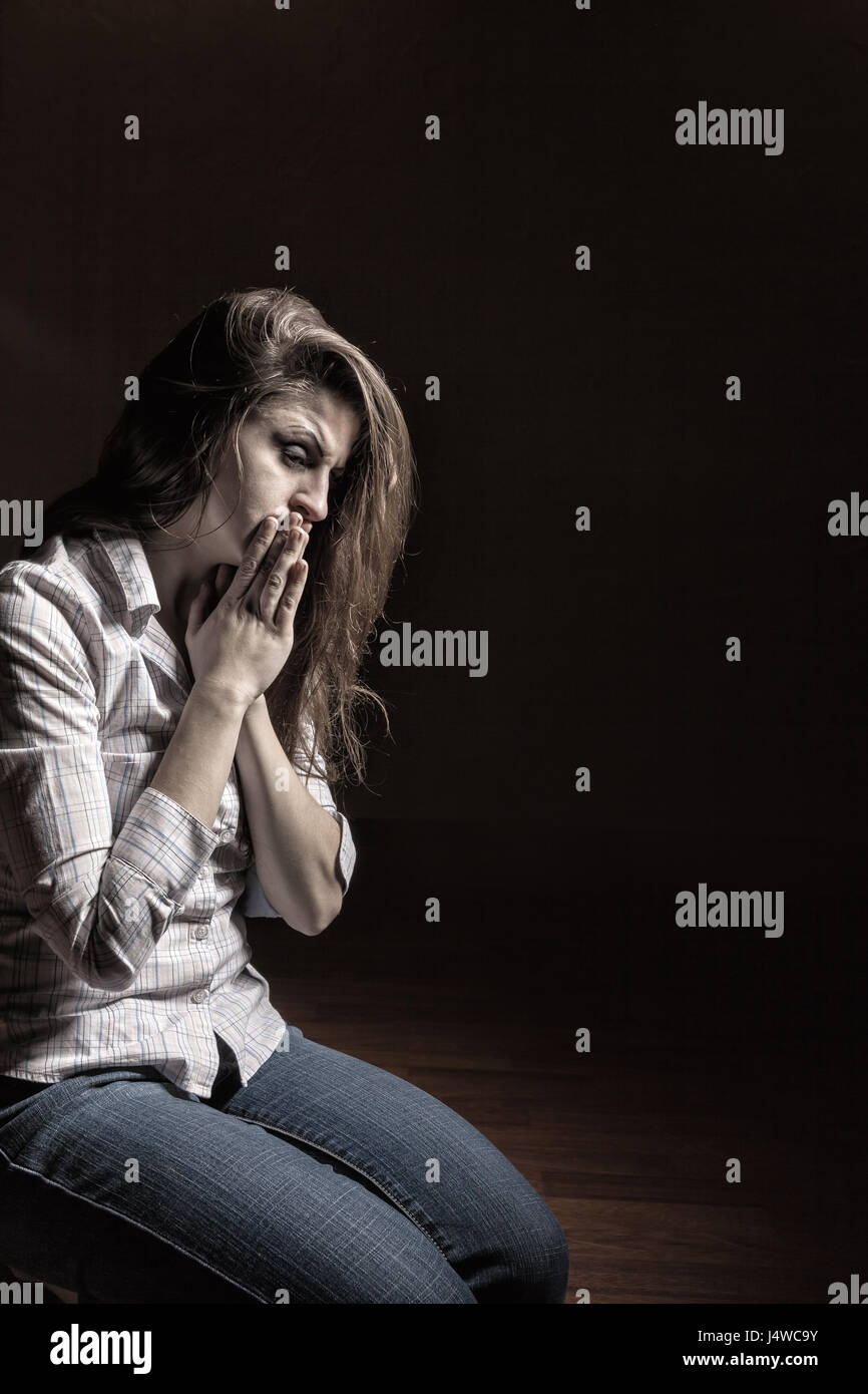 Sad woman sitting alone in a empty room Stock Photo