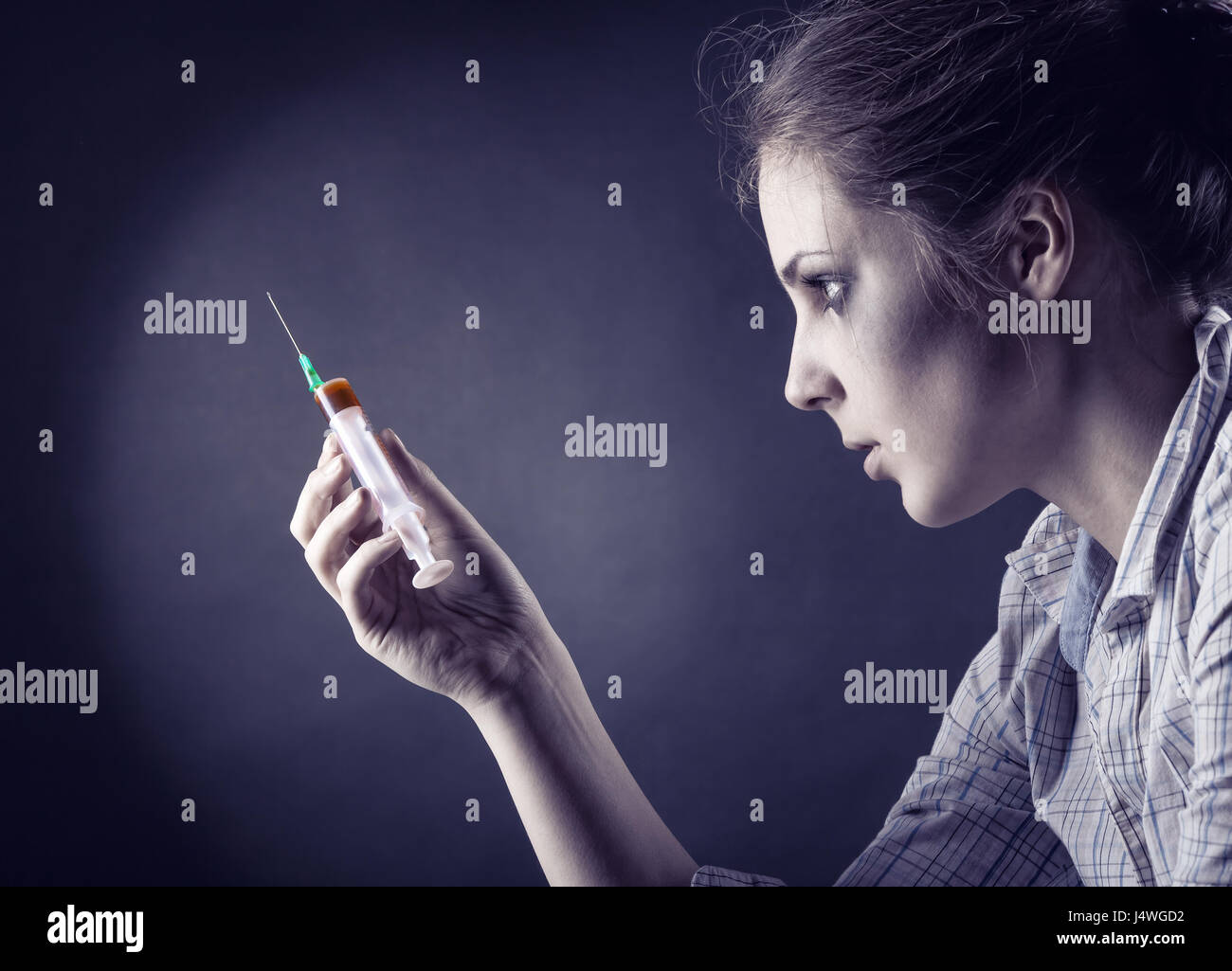 Young woman with drug addiction on dark background. Side view Stock Photo