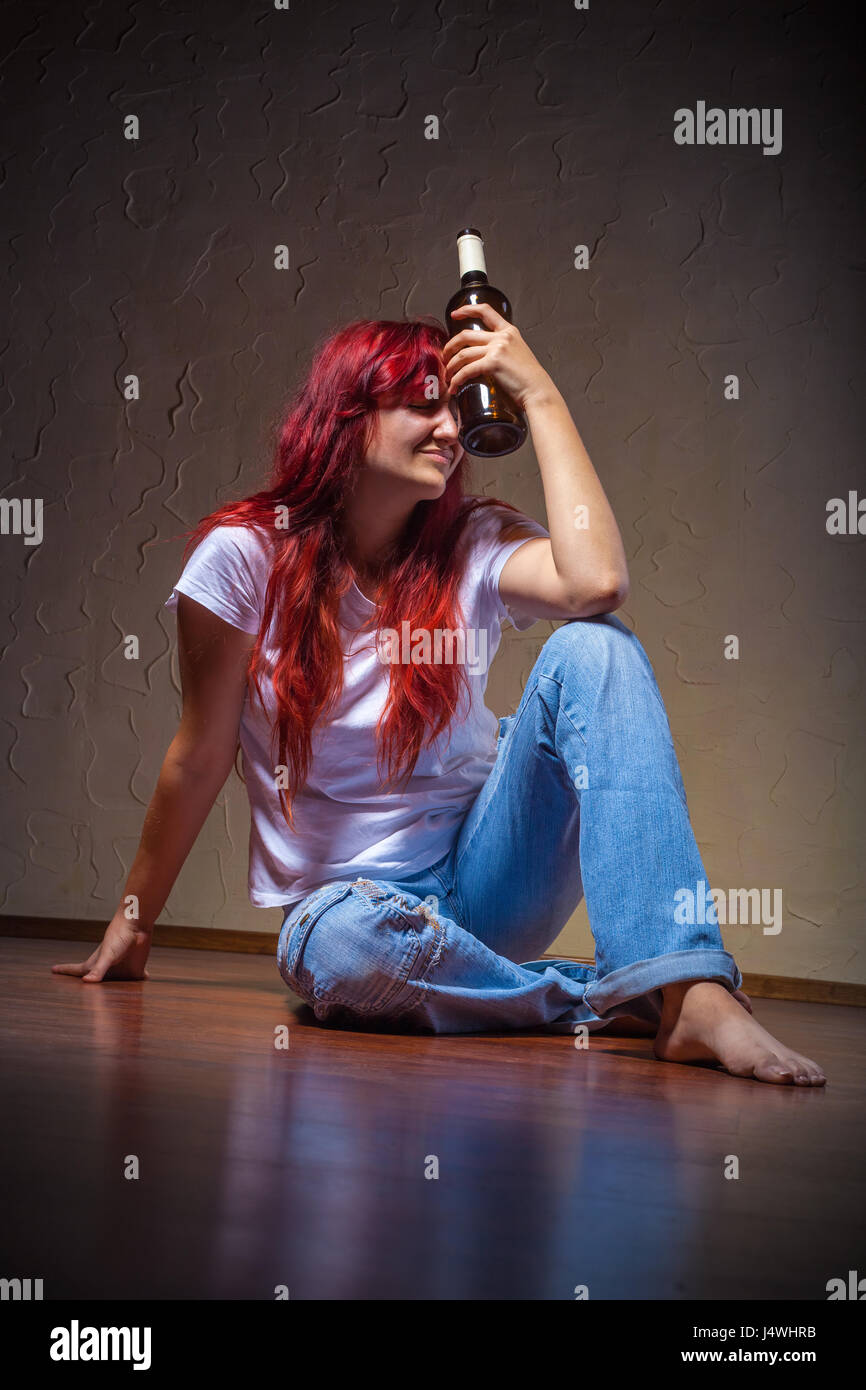 A young woman from a bottle of wine-drinking at home sitting on the floor Stock Photo