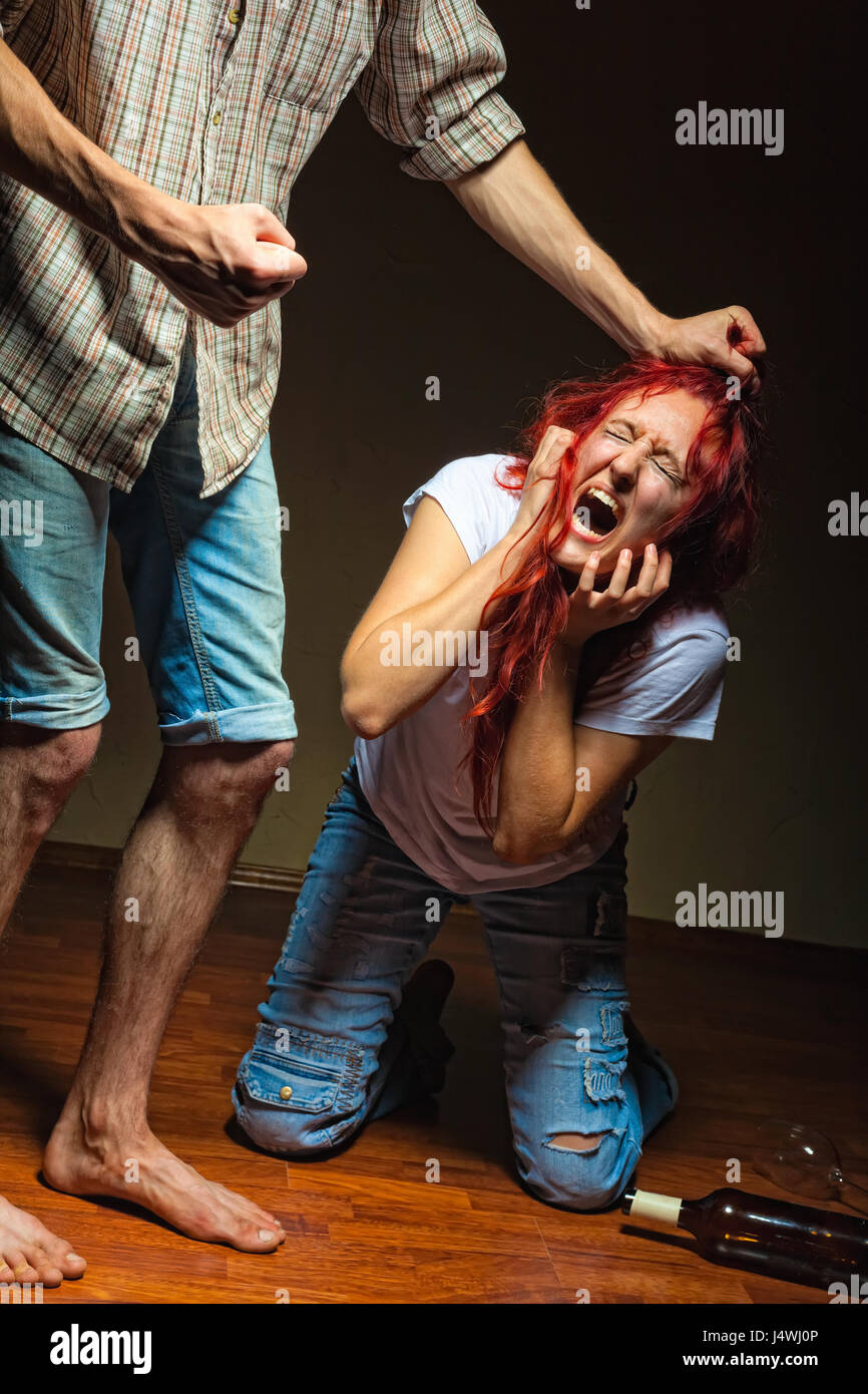 The man grabbed his wife by the hair with the requirements to stop drinking alcohol Stock Photo