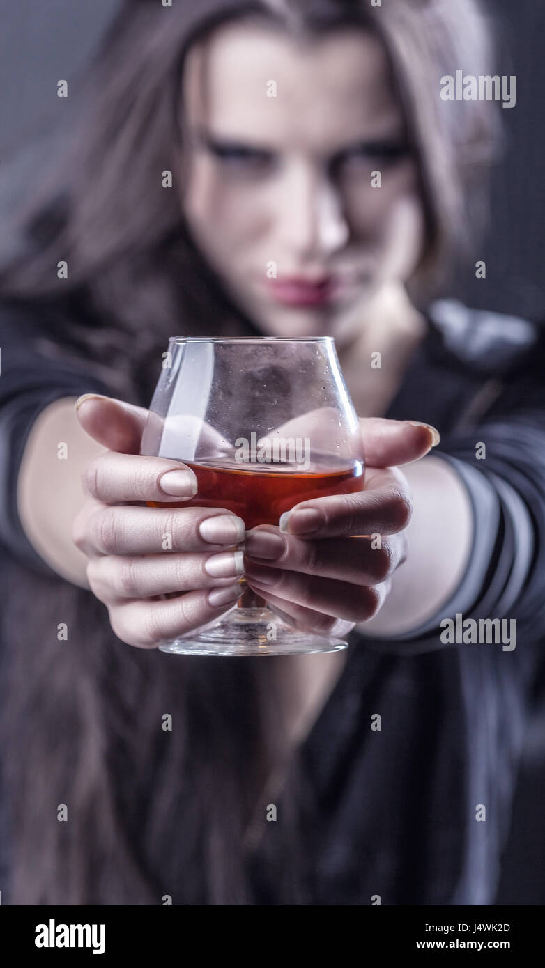 Young woman in depression, drinking alcohol. Focus on glass Stock Photo