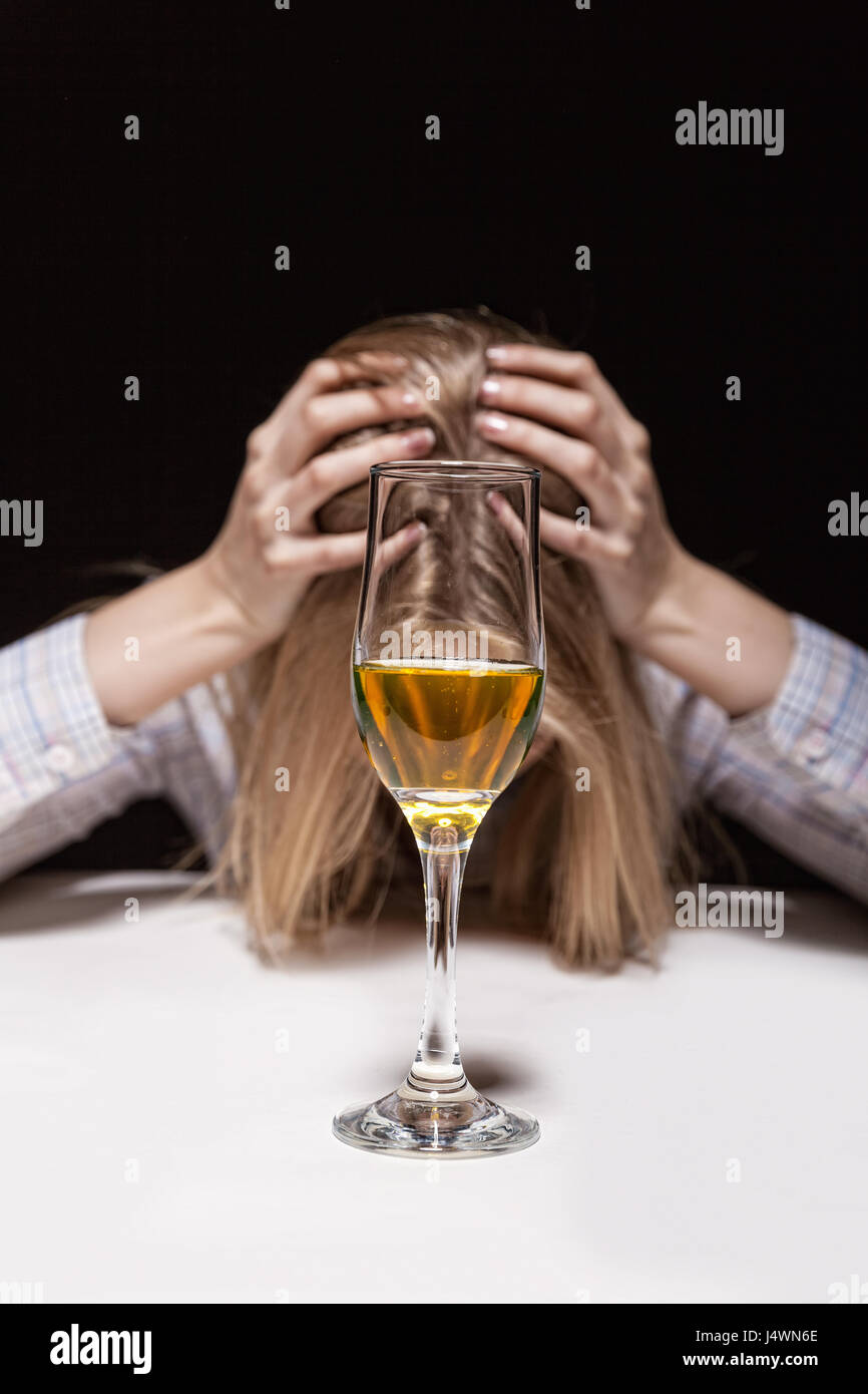 Young beautiful woman in depression, drinking alcohol on dark background Stock Photo