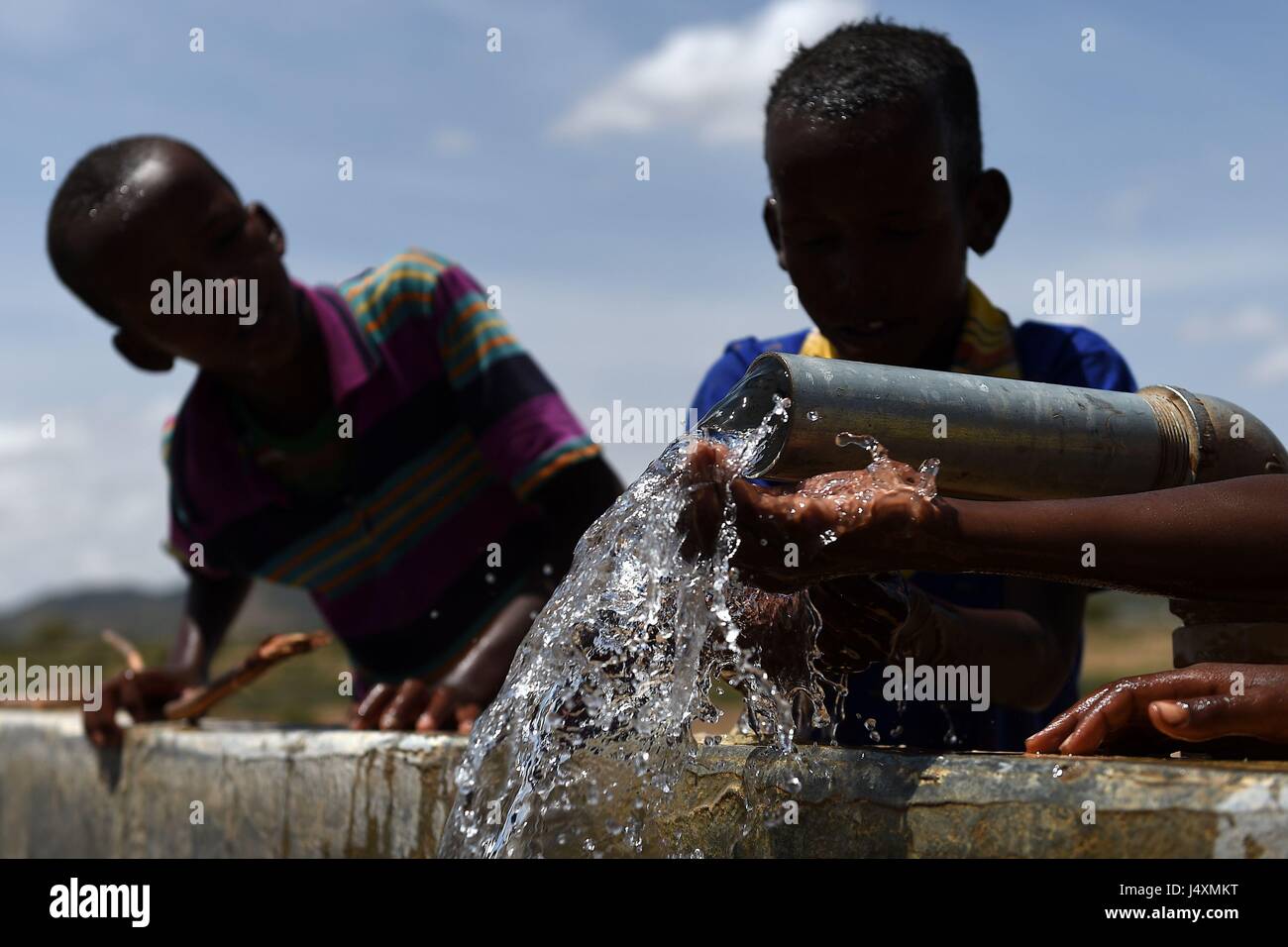 Children wash with water from a pipeline in the village of Afraaga, Somaliland where charity CARE International have built a storage tank and installed pipelines and taps to give villagers access to clean water from a nearby borehole. Stock Photo